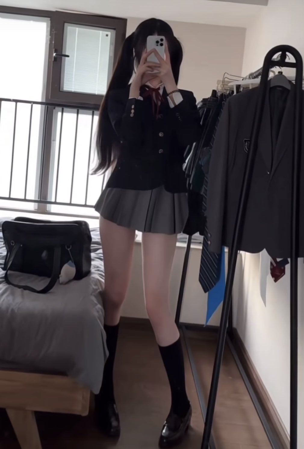 穿着黑色服装和红色领带的女人站在衣柜前面。