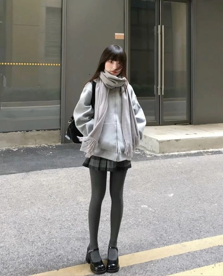 一位女人穿着灰色的胡迪和一件衬衫。