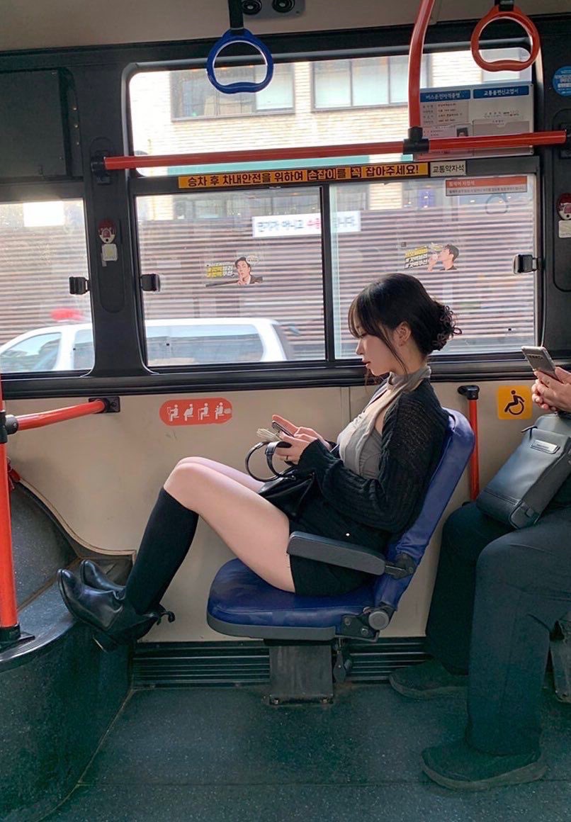 穿着灰色衬衫的女人坐在公交车上写短信。