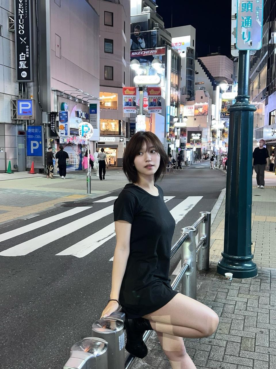 穿着黑色衣服的女人坐在一个城市的围栏上。