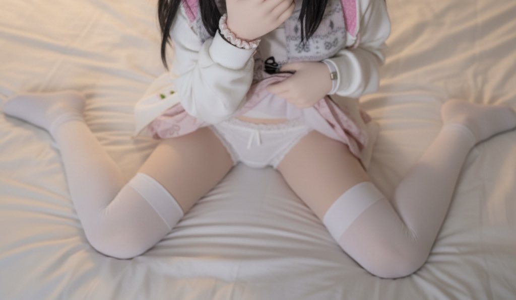 穿着白色裙子和白色袜子的女人坐在床上。