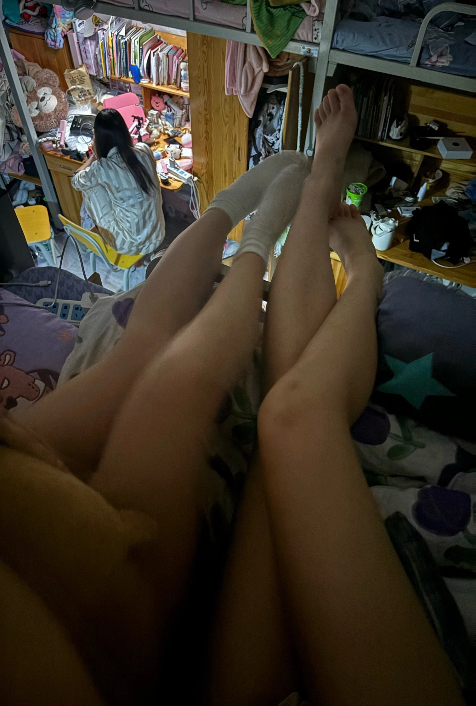 两个女孩躺在床上,双腿交叉。