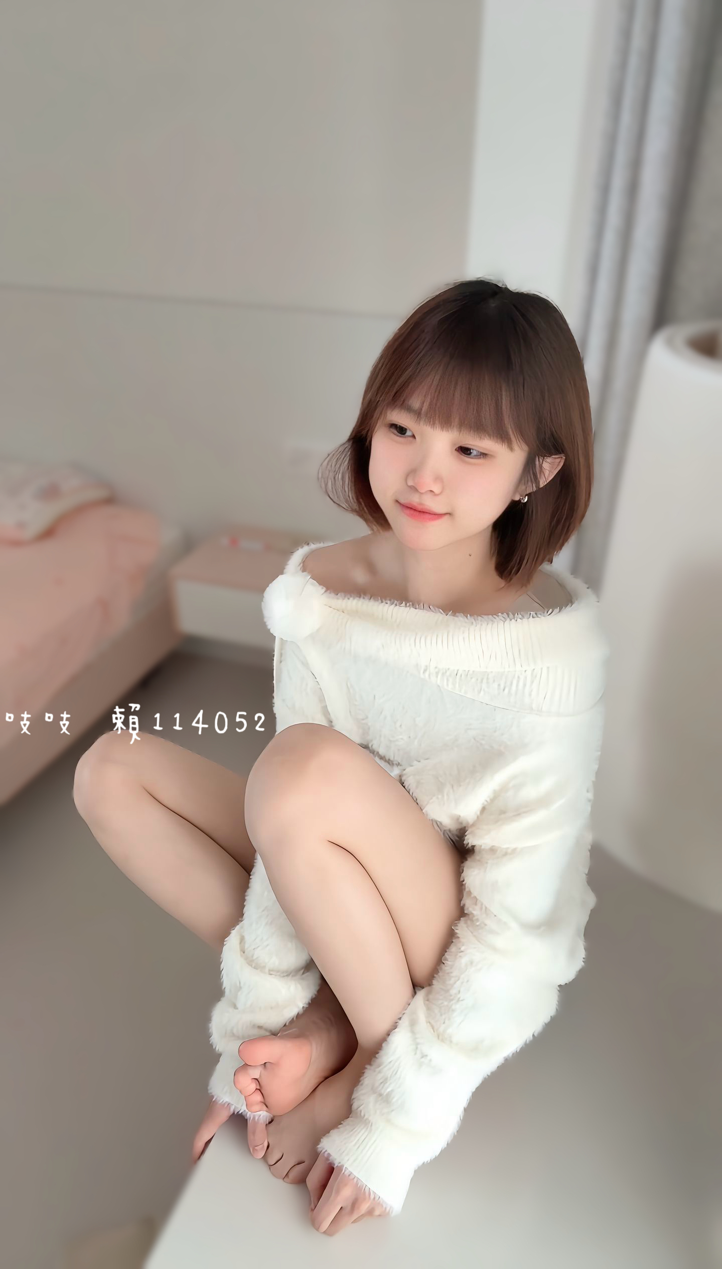 女人穿着白色衬衫,坐在床上。