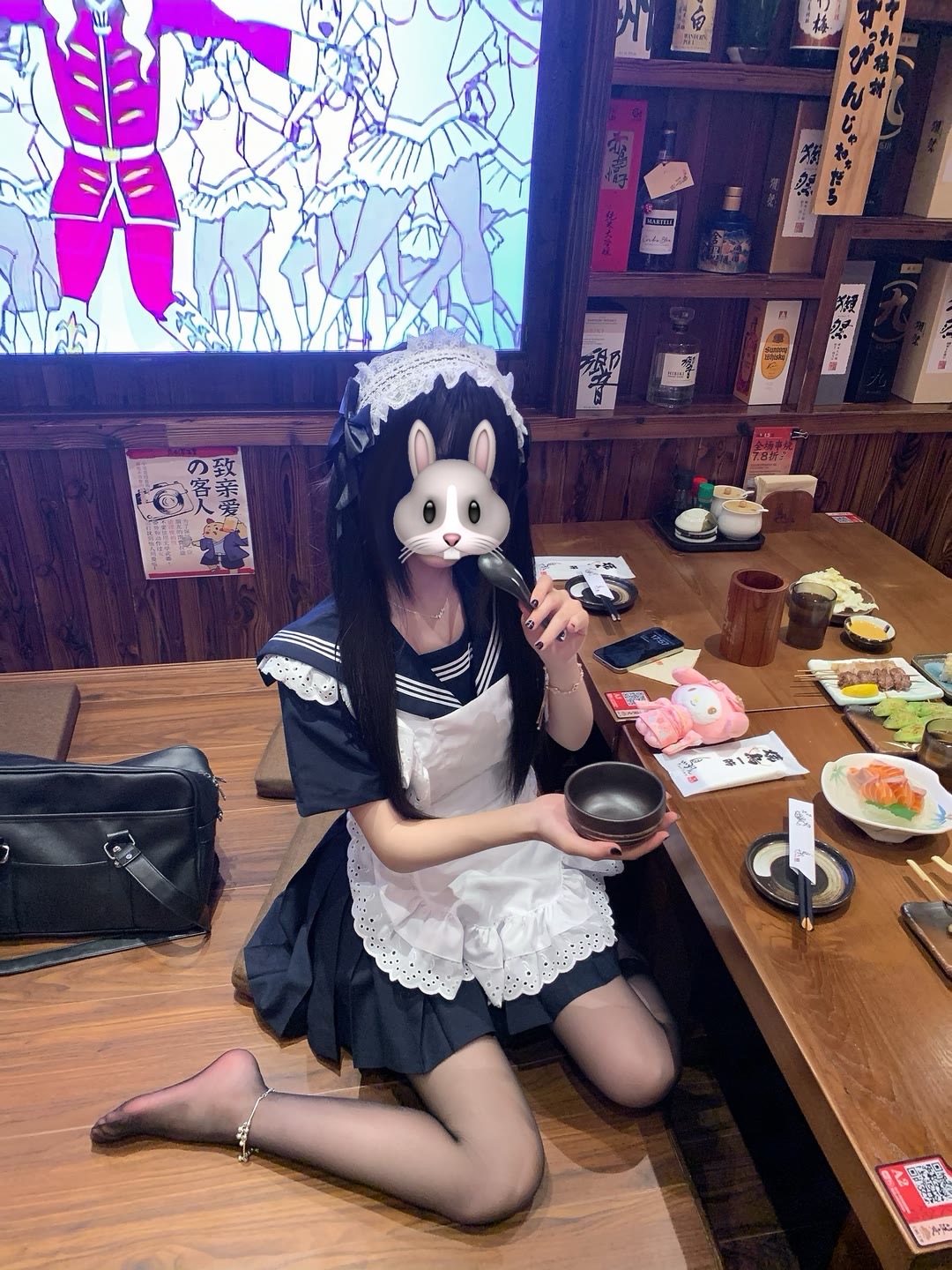 穿着女仆的衣服的女人坐在一张桌子上。