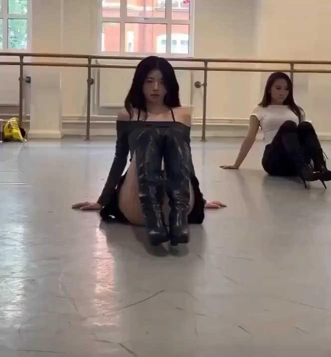 穿着黑靴子和黑裙子的女人坐在地板上。