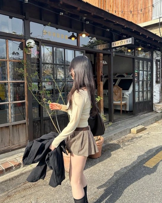 长头发和一件黑色夹克的女人走在街上。