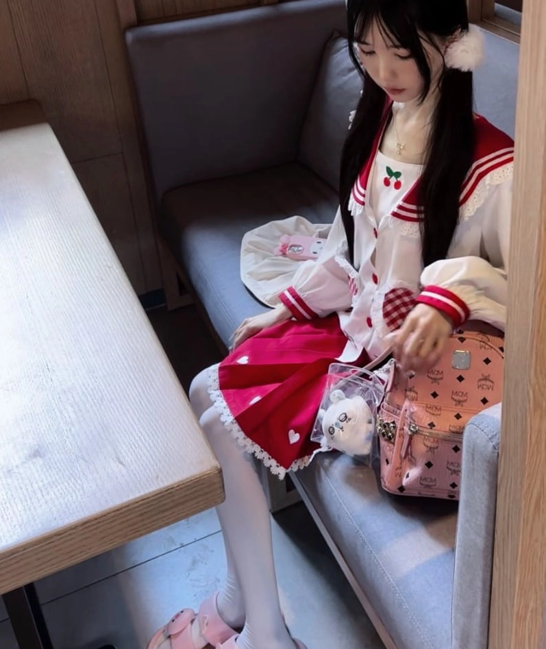 一只戴着白色帽子和红色裙子的娃娃坐在沙发上。