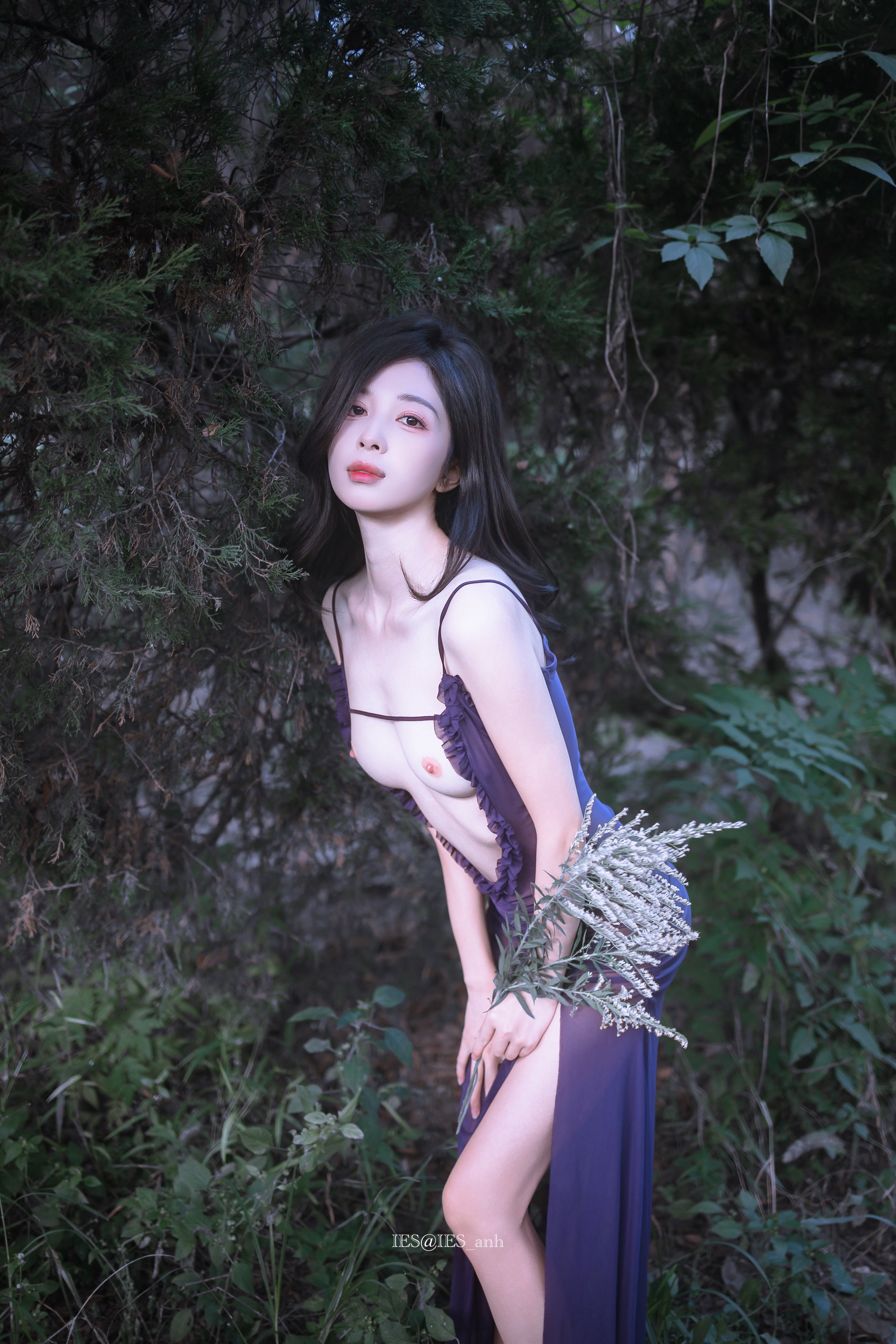 穿紫色衣服的女人站在树林里。