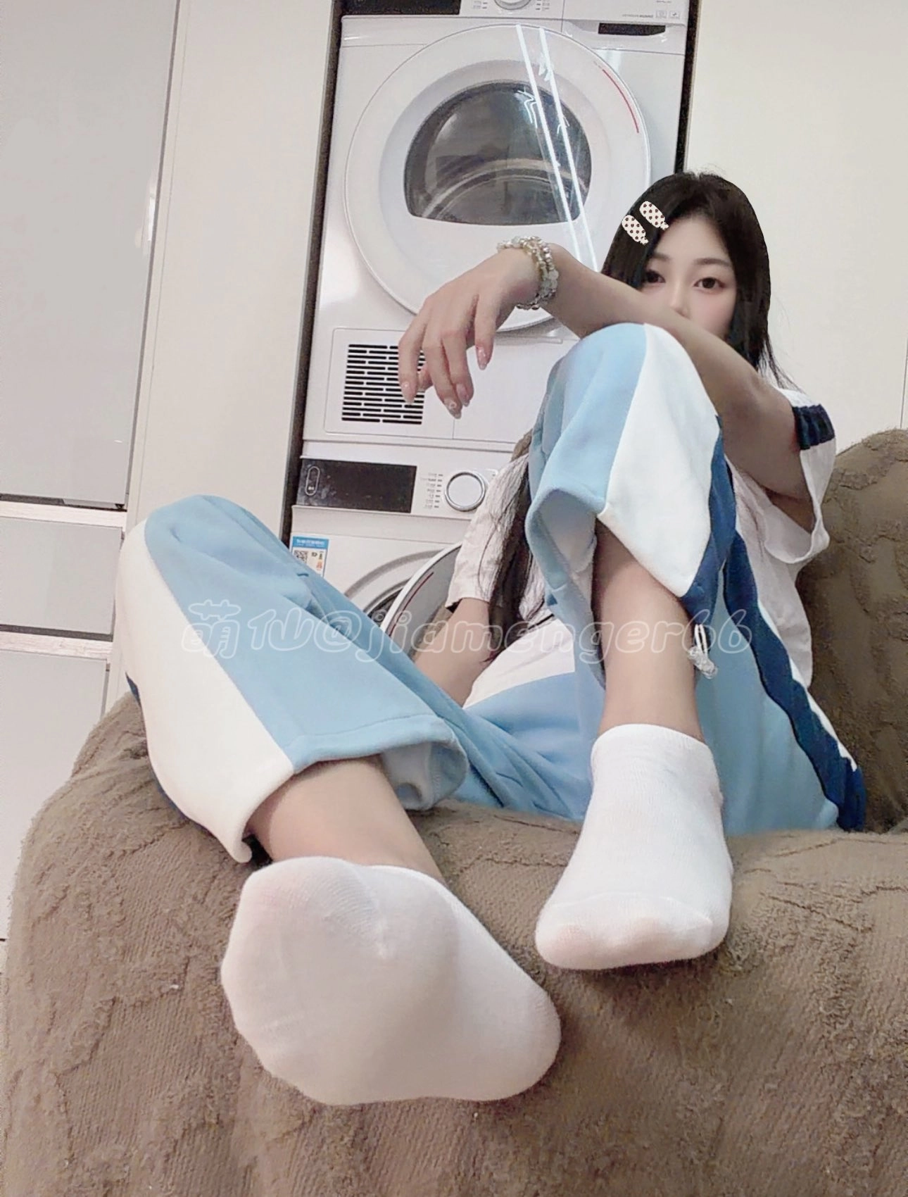 女孩坐在沙发上,穿着蓝色裤子和一件白色衬衫。