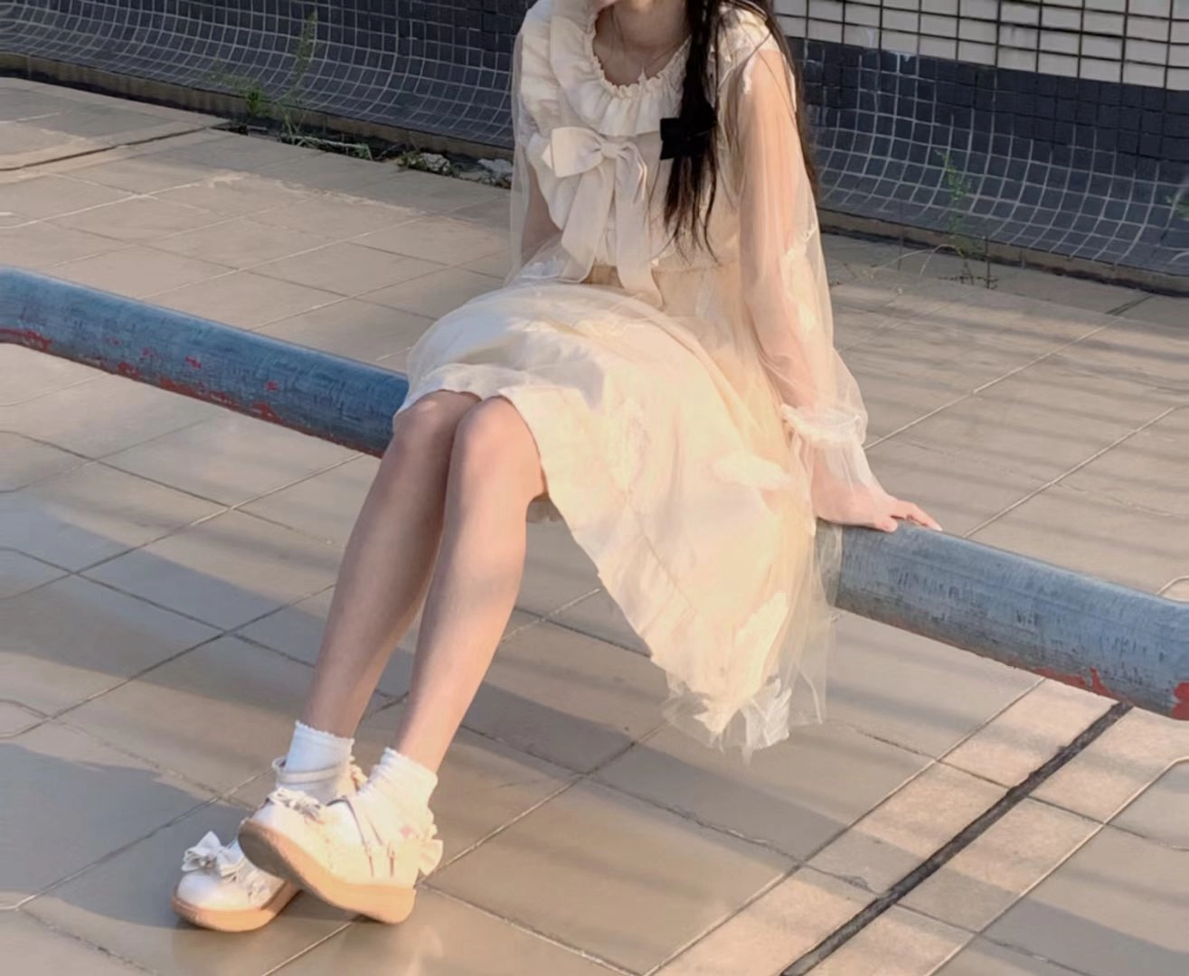 穿着白色裙子的女人坐在一个凳子上。