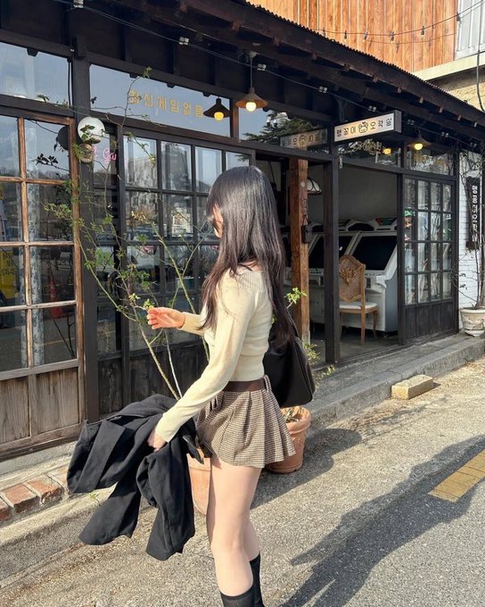 长头发和一件黑色夹克的女人走在街上。