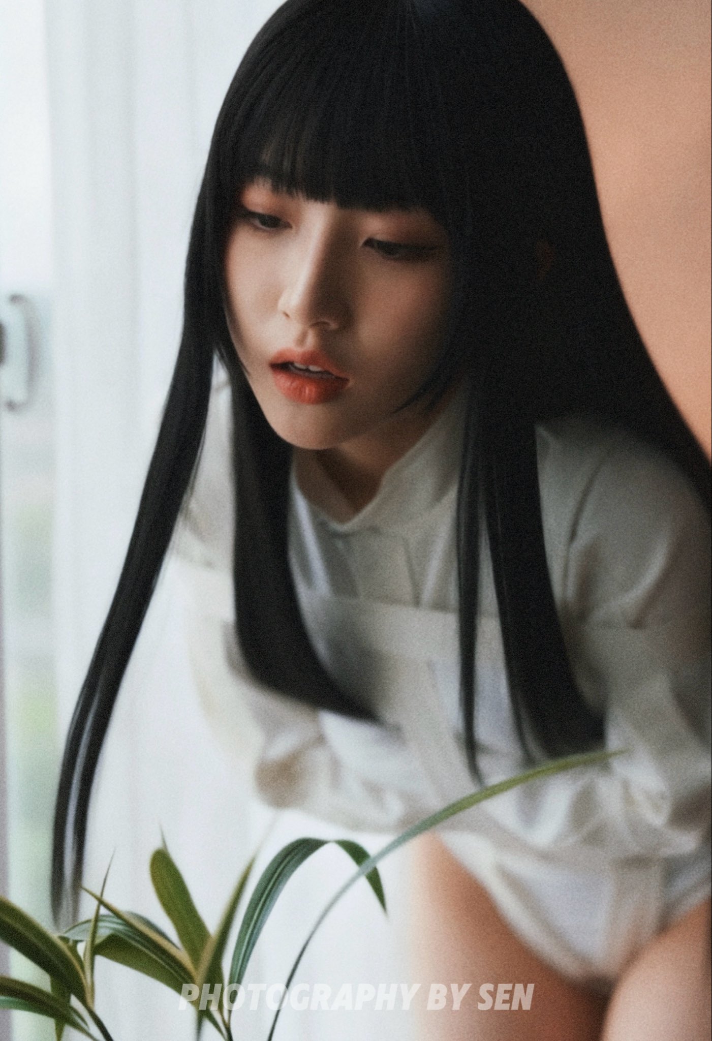 穿着白色衬衫和白裤子的女人站在窗前。