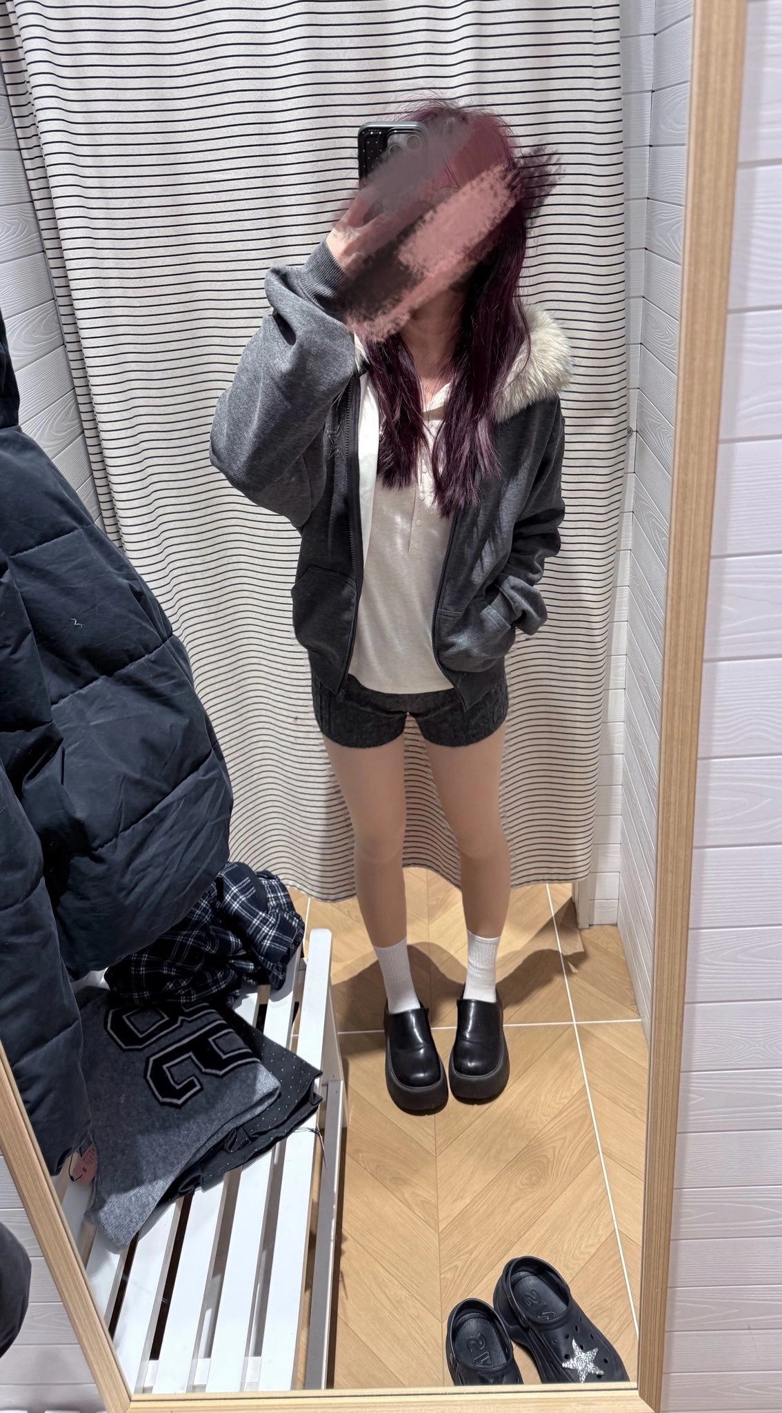 一位穿着灰色夹克和白色衬衫的女人在镜子里拍了一张自拍。