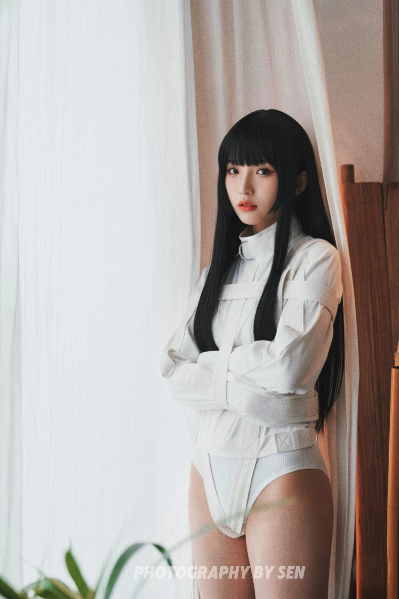 穿着白色衬衫和白裤子的女人站在窗前。