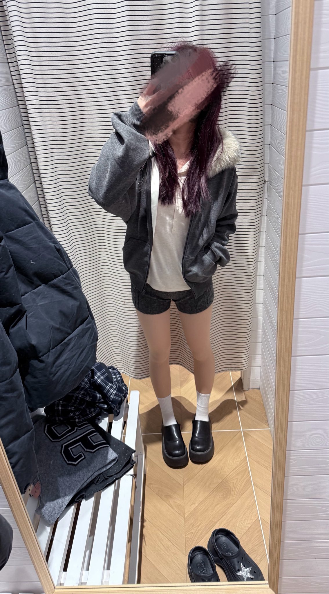 一位穿着灰色夹克和白色衬衫的女人在镜子里拍了一张自拍。