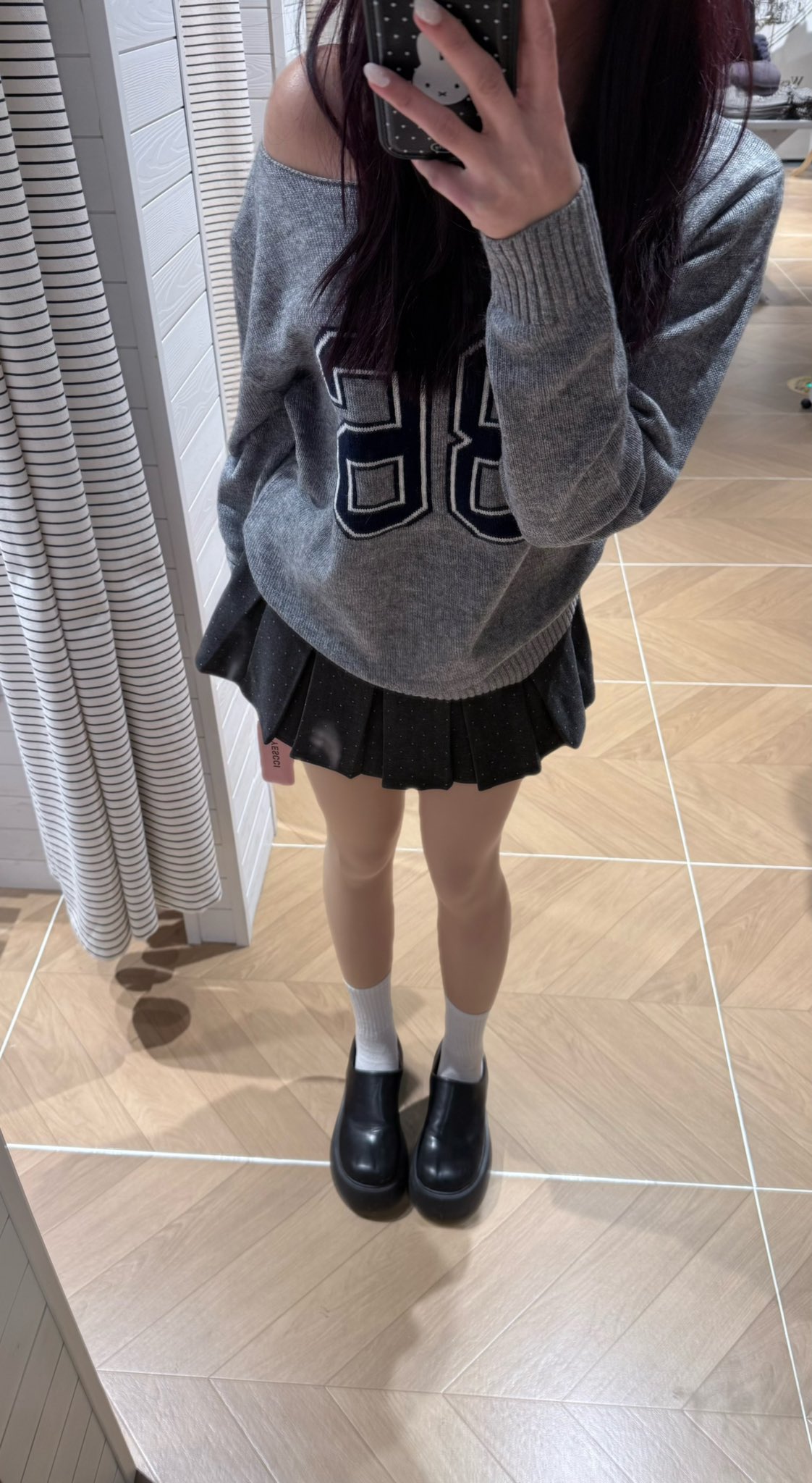 一位穿着灰色夹克和白色衬衫的女人在镜子里拍了一张自拍。