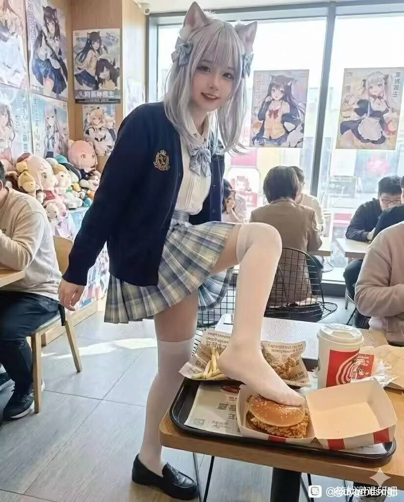 一位穿着蓝色夹克和白色袜子的女孩坐在桌子上,脚在汉堡里。