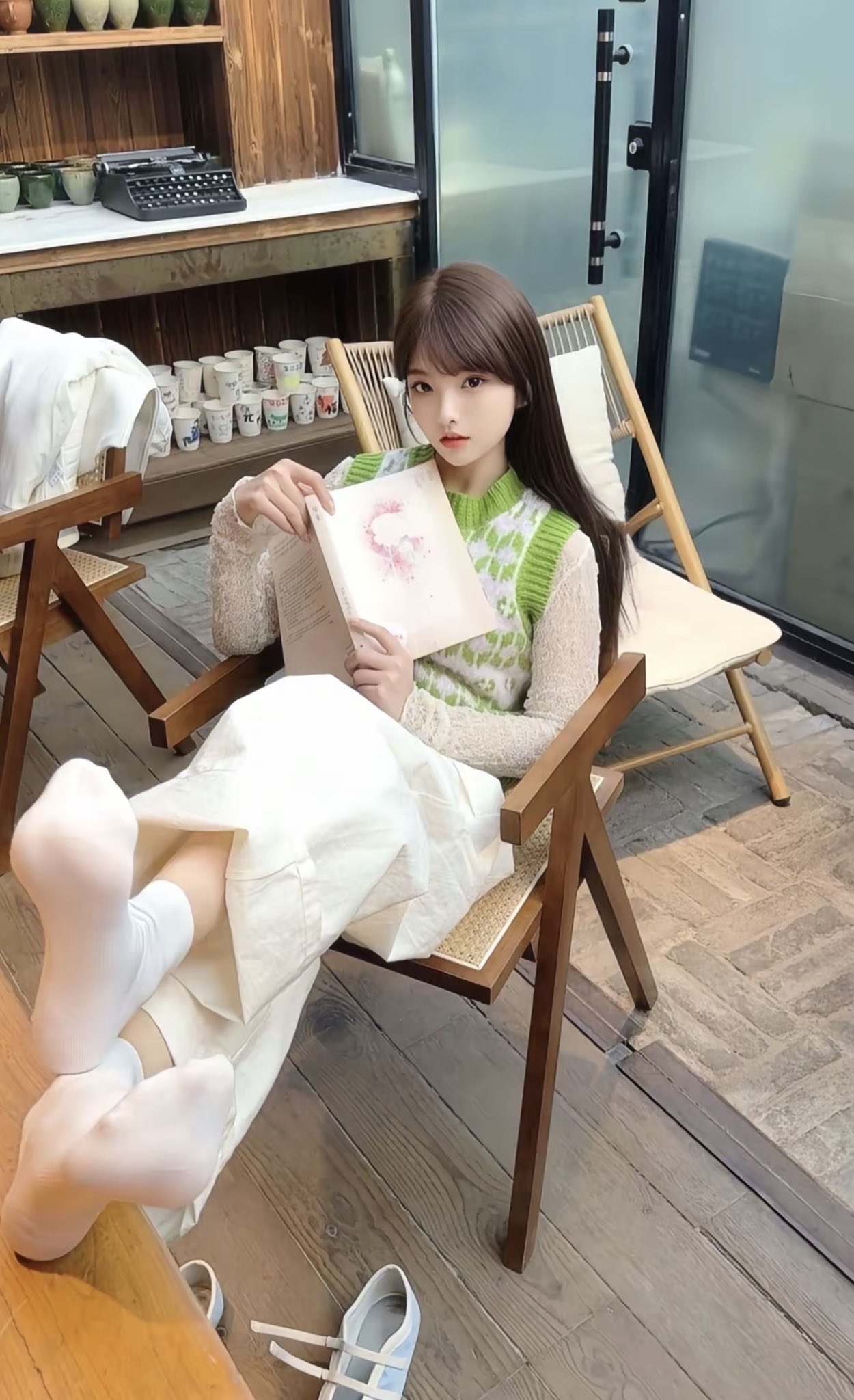 一位穿着绿色衬衫的女人坐在椅子上,读一本书。