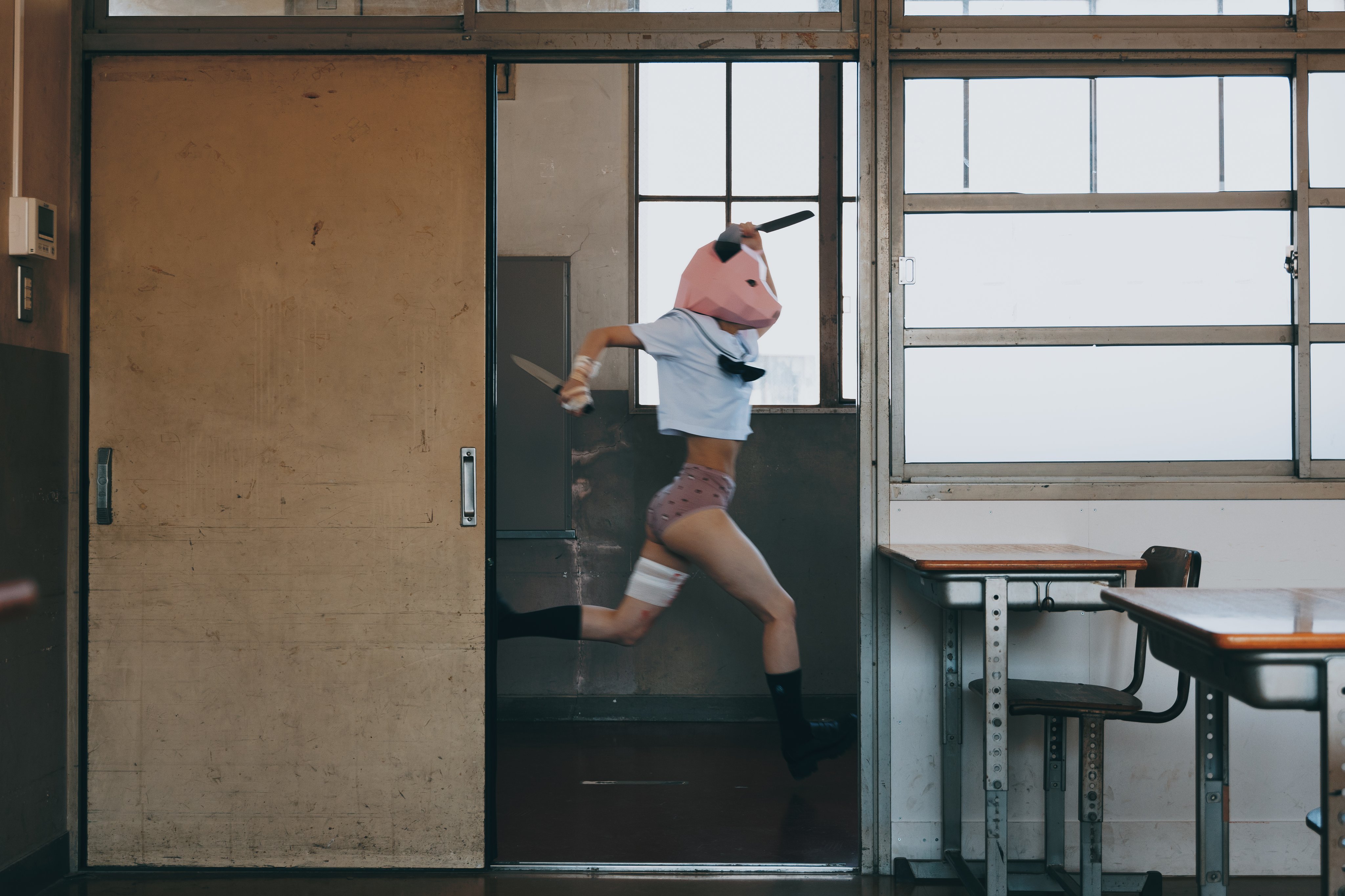 戴着猪面具的女孩坐在桌子上。