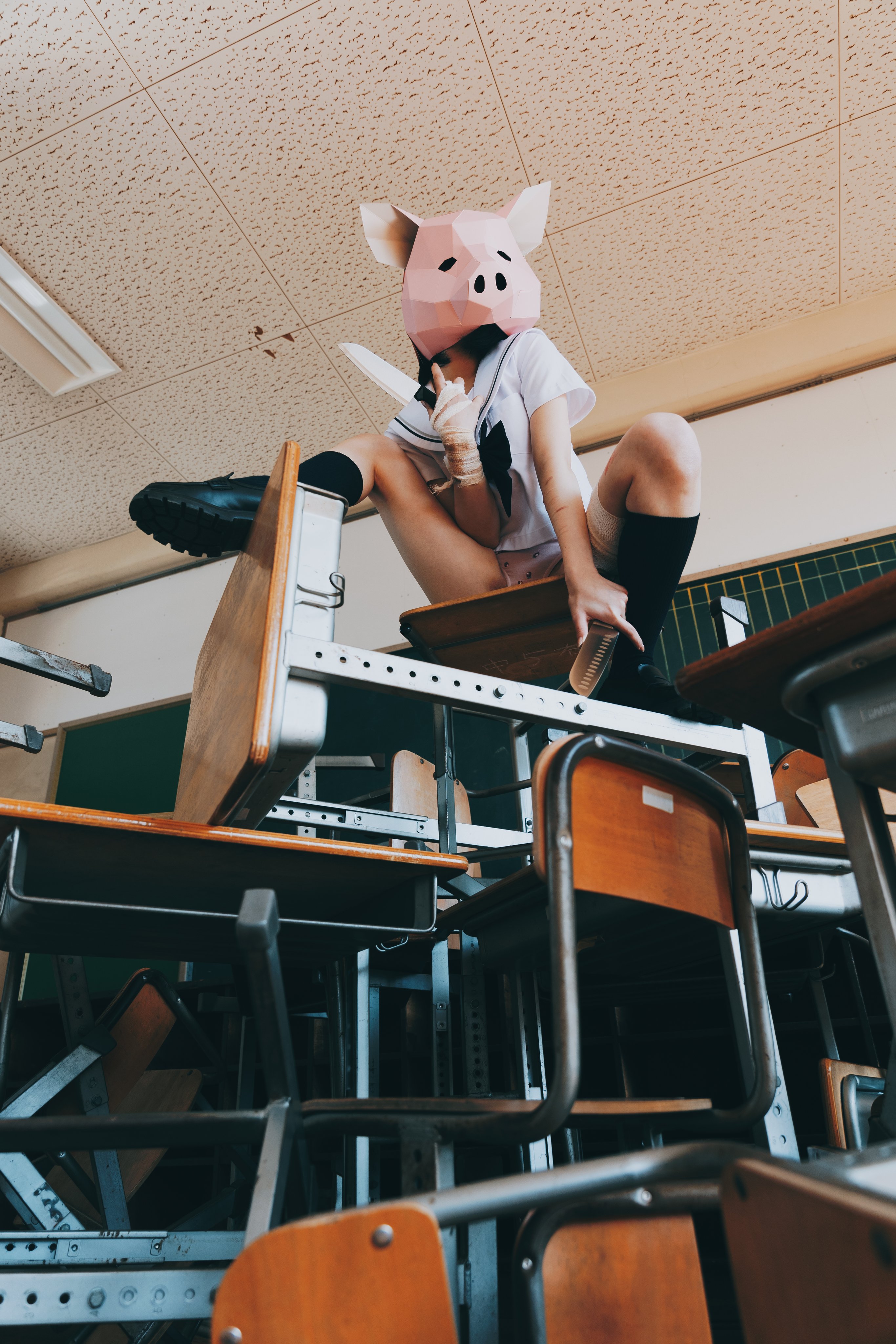 戴着猪面具的女孩坐在桌子上。