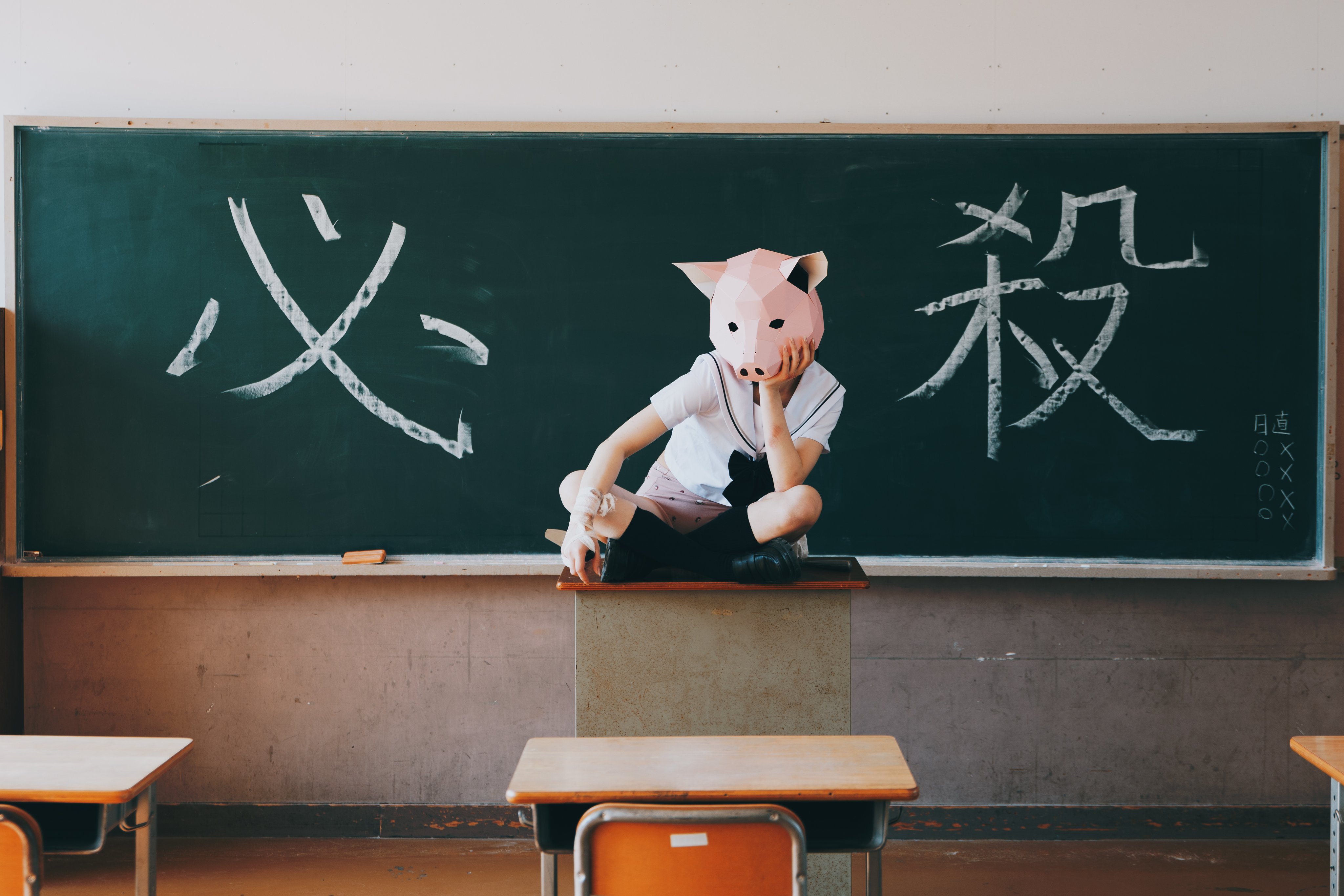 戴着猪面具的女孩坐在桌子上。