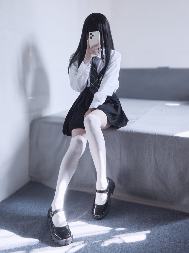 女孩坐在床上,拿着手机。