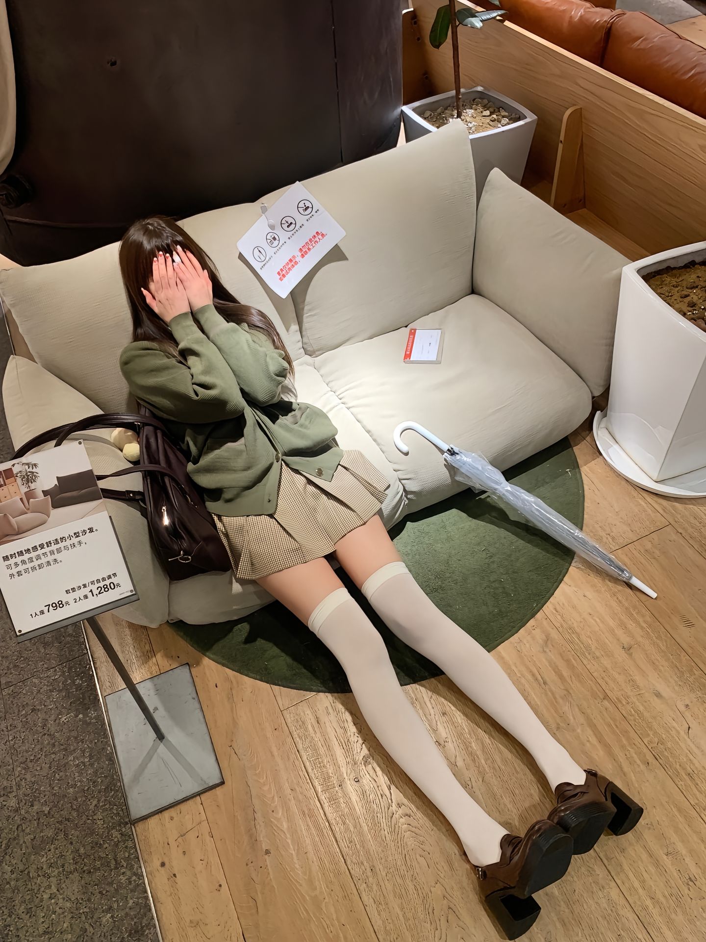 女人坐在沙发上,带着一个钱包和伞。