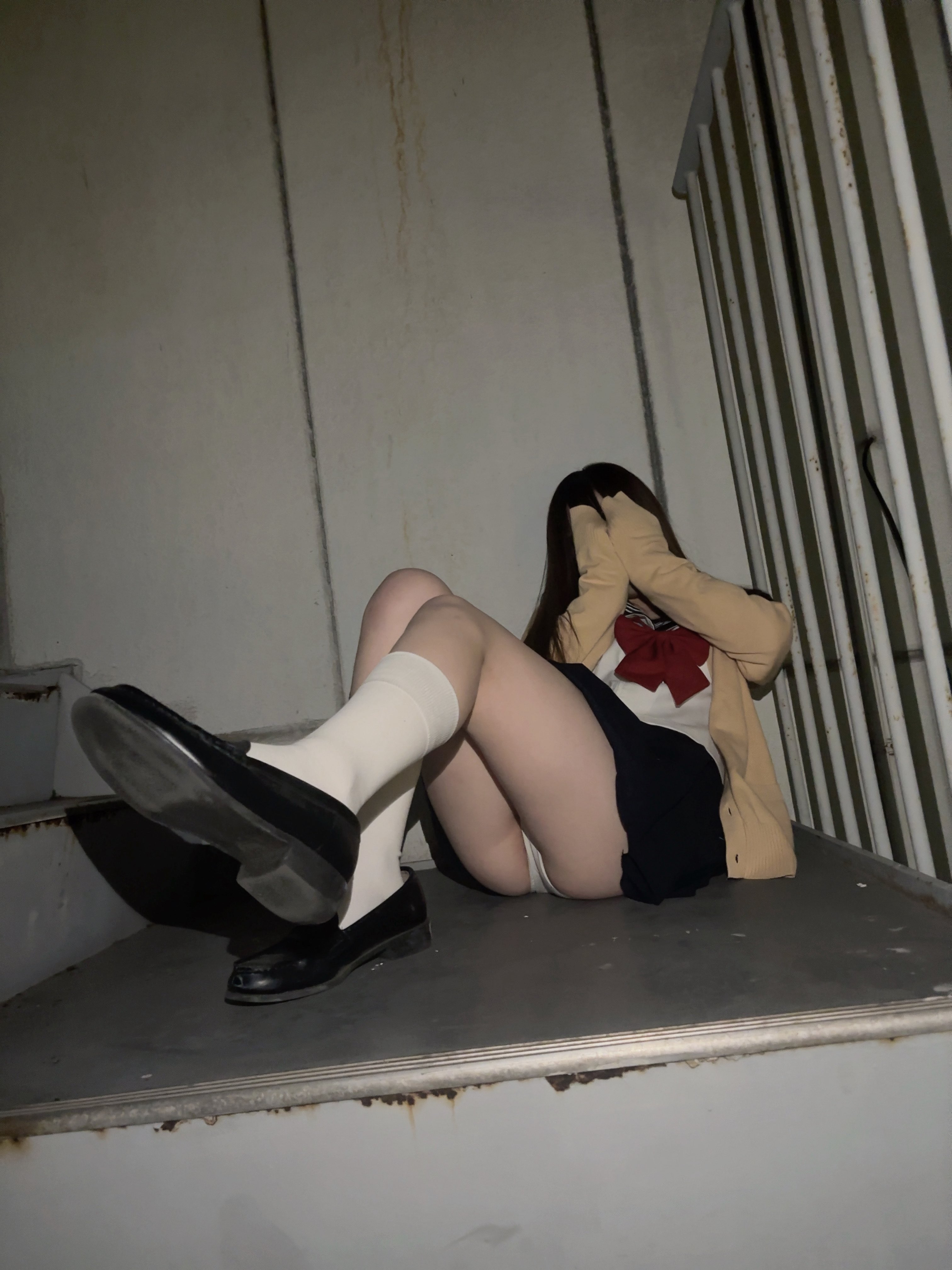 穿着学校制服的女人坐在楼梯上。