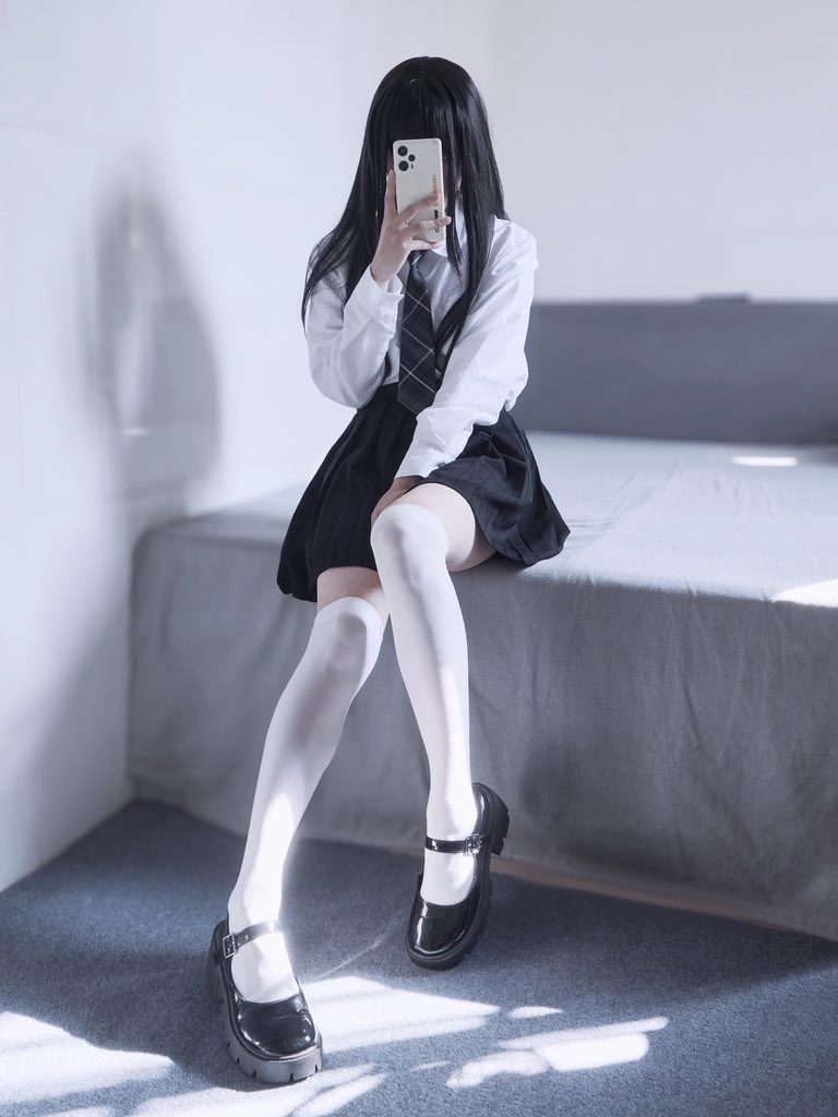 女孩坐在床上,拿着手机。