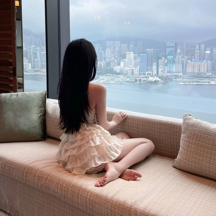 一位穿着白衣的女人坐在沙发上,俯瞰着一座城市。