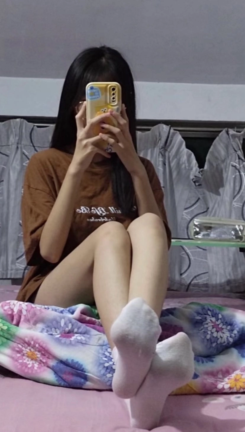 女人坐在床上,拿着手机。