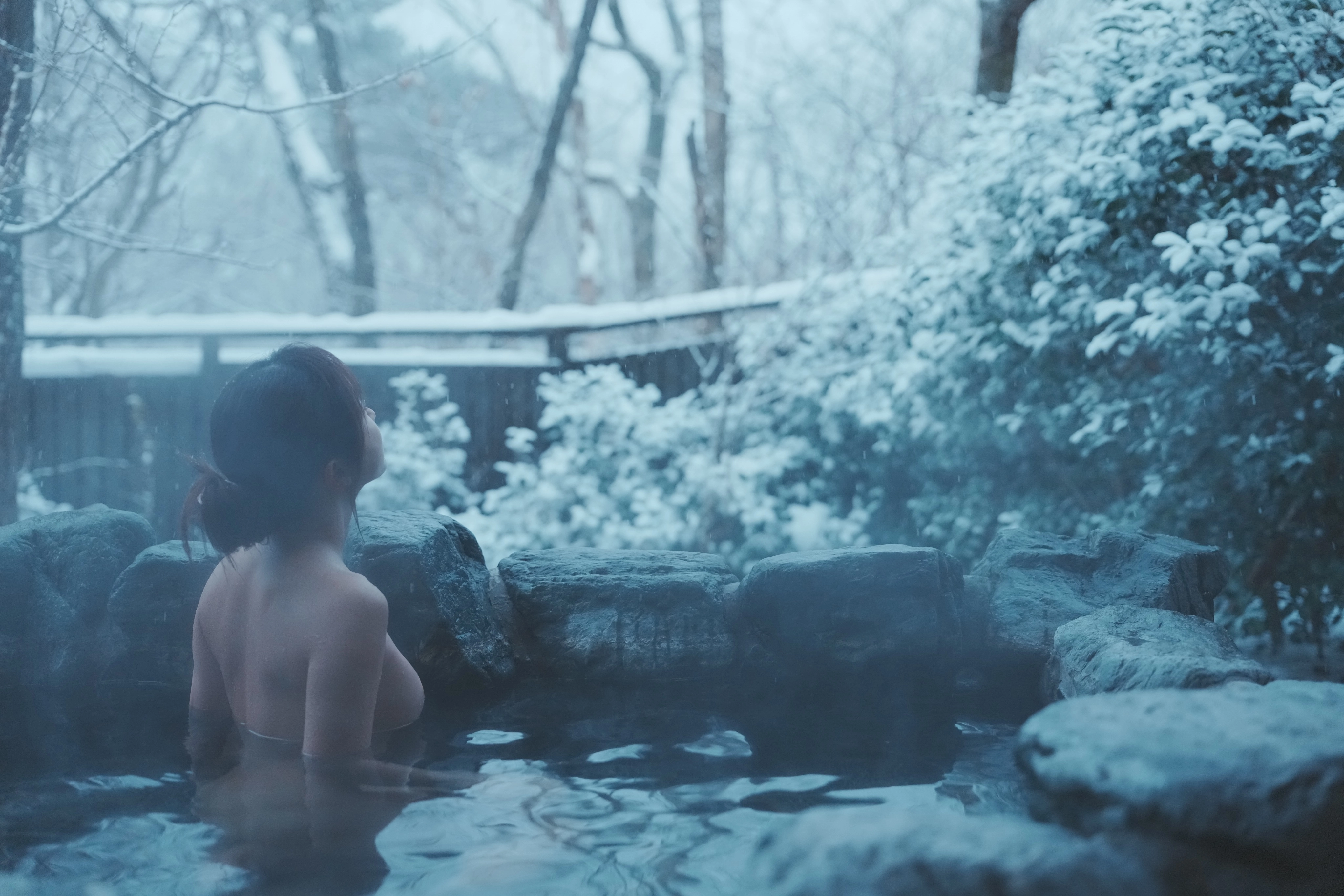 女人在泡沫浴室里,雪落在外面。