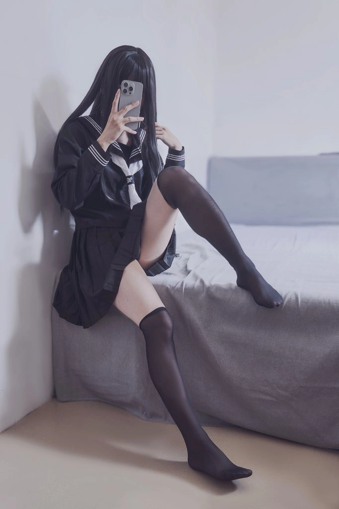 穿着黑色衬衫和黑裤子的女人坐在床上。