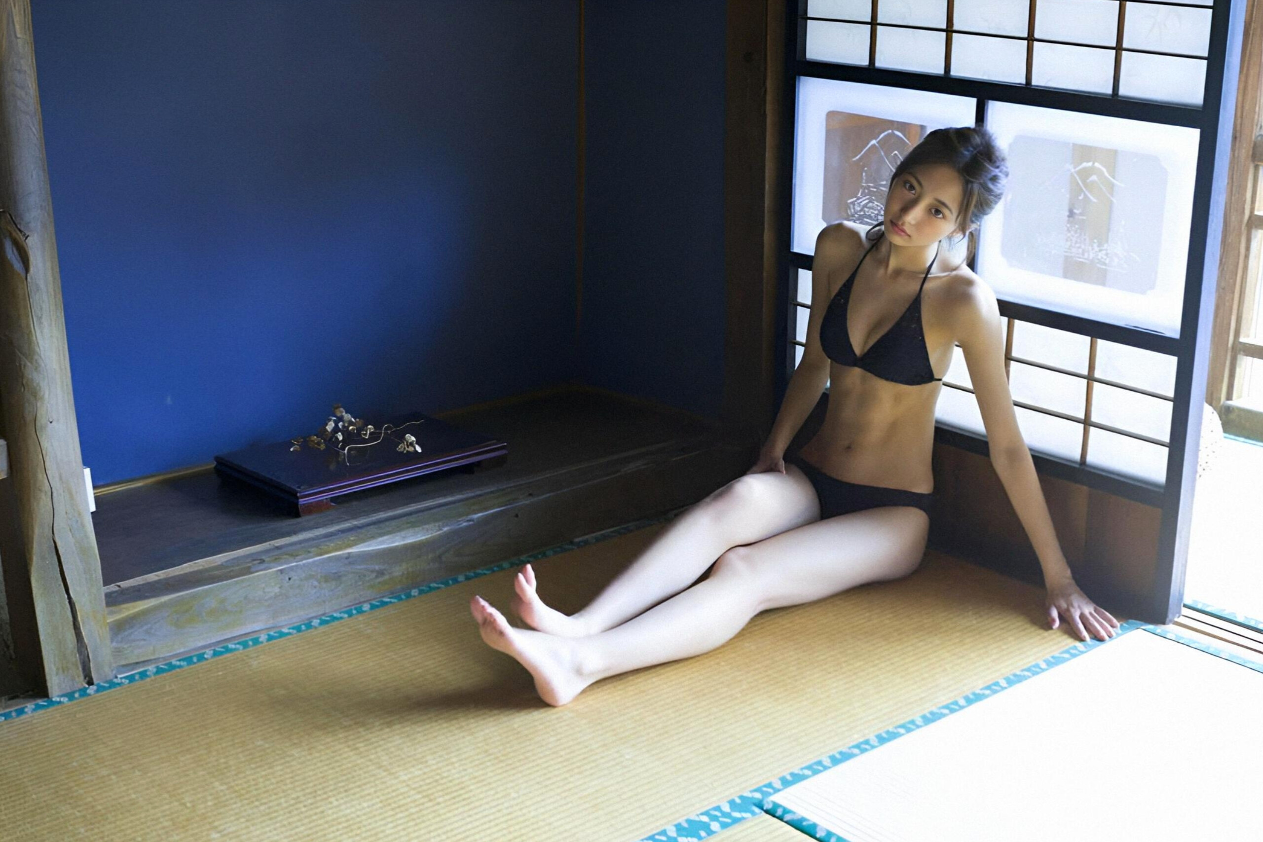 穿着黑色比基尼的女人坐在一个凳子上。