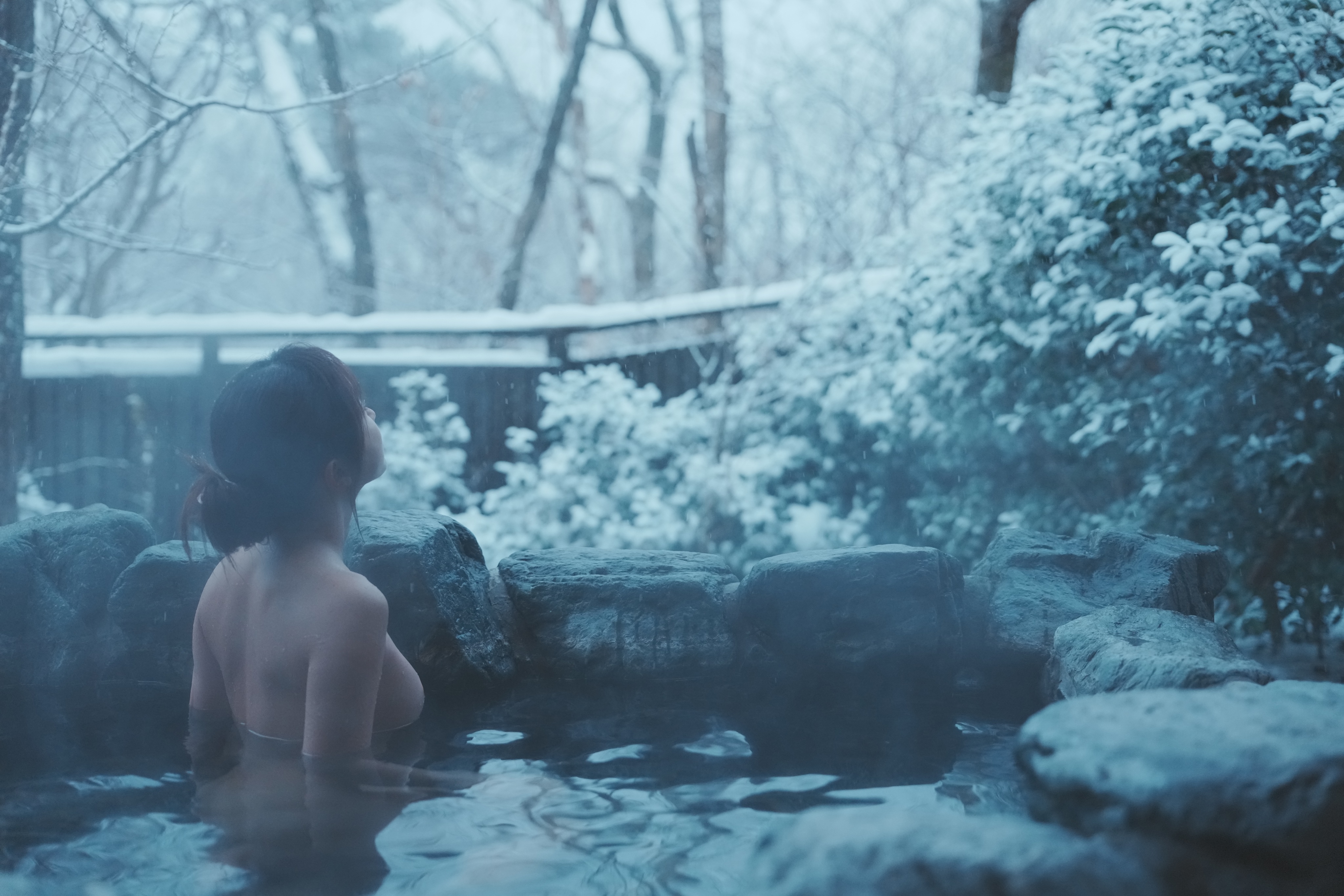 女人在泡沫浴室里,雪落在外面。