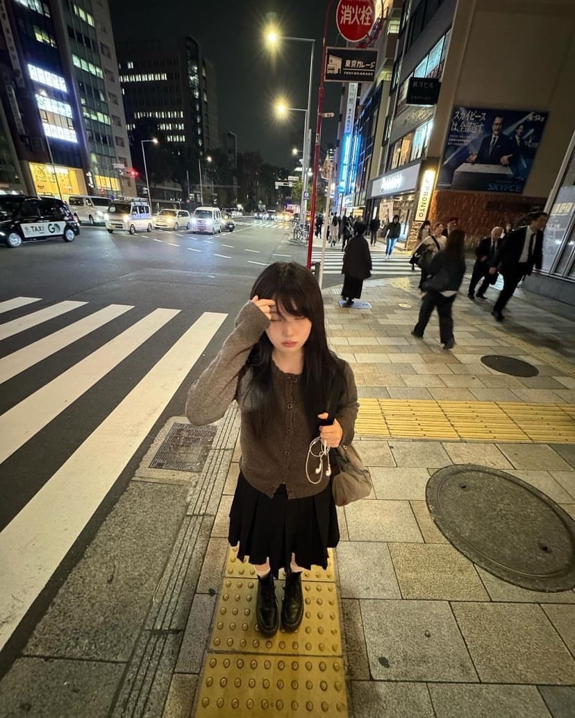 穿着灰色衬衫和黑色衬衫的女人站在一个黄色的线上。