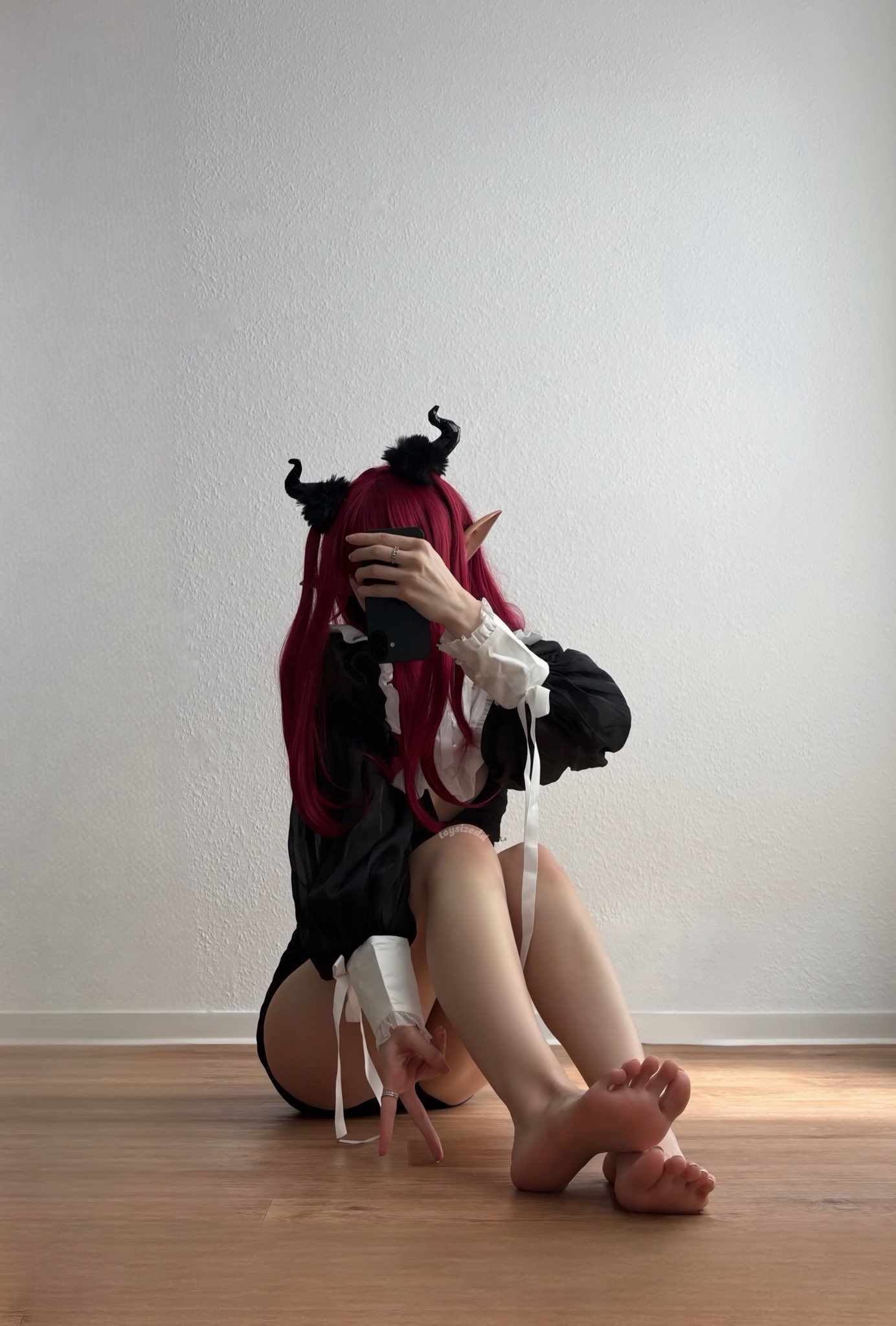 一位戴着角和黑色裙子的女人正在拍照。