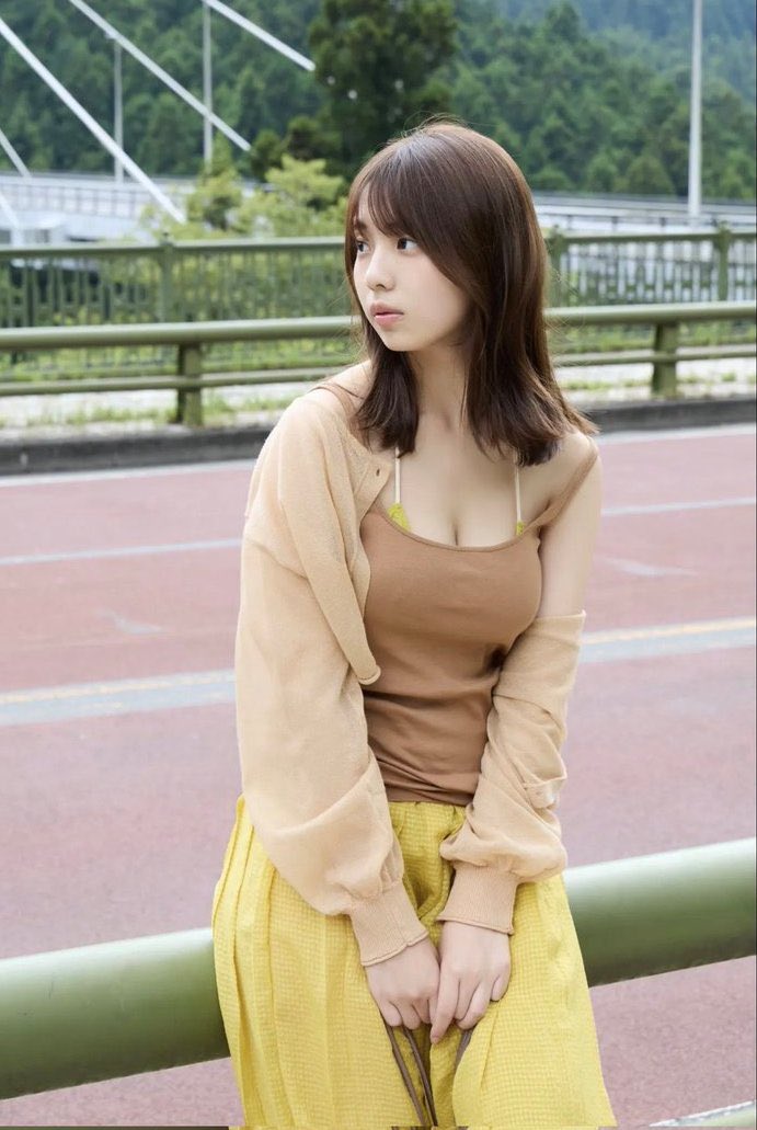 一位穿着棕色衬衫和黄色裙子的女人站在桥上。