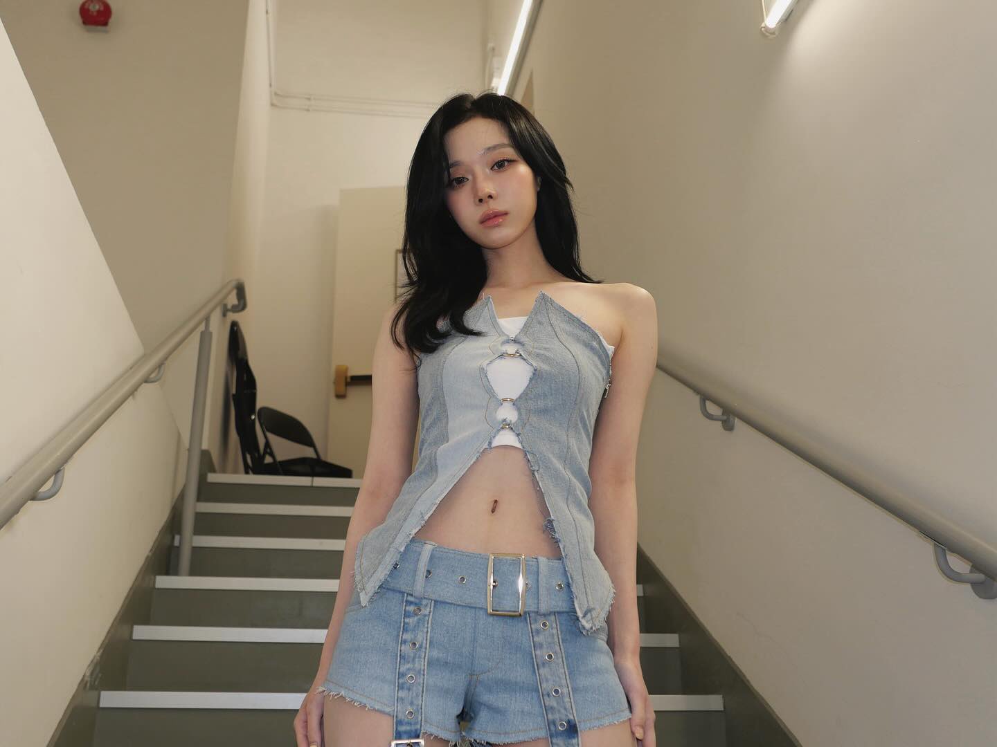 一位穿着蓝色衬衫和短裤的女人站在楼梯上。