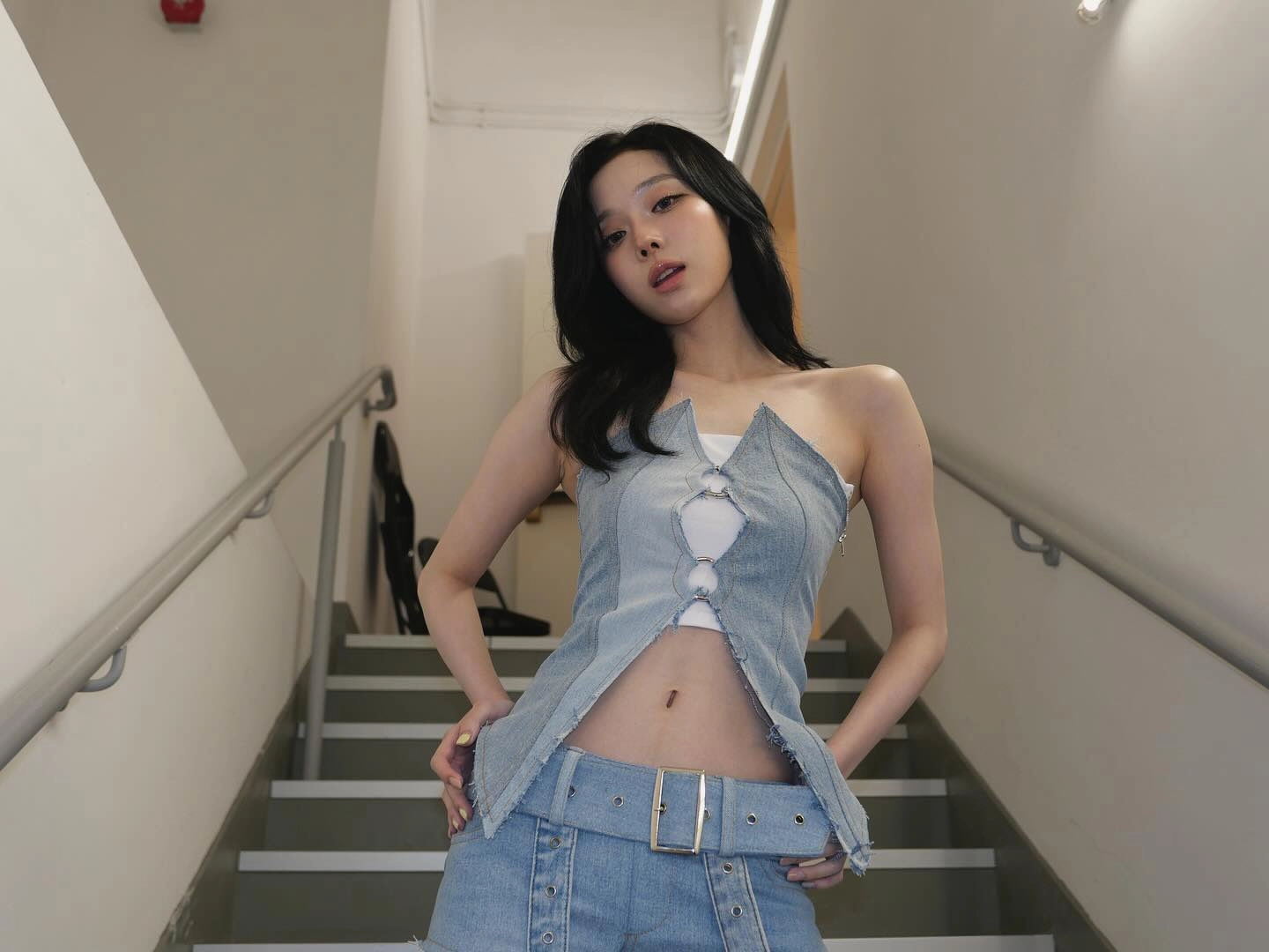 一位穿着蓝色衬衫和短裤的女人站在楼梯上。