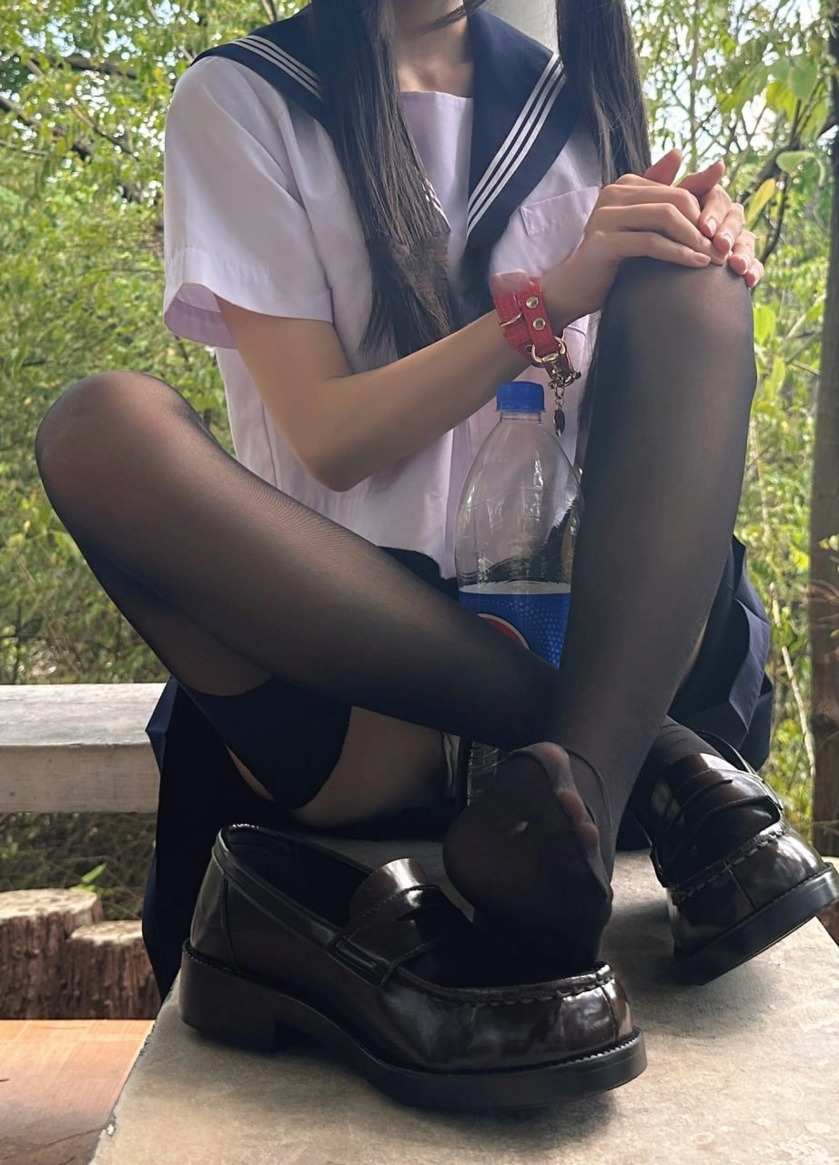 女孩坐在一个凳子上,手里拿着一瓶水。