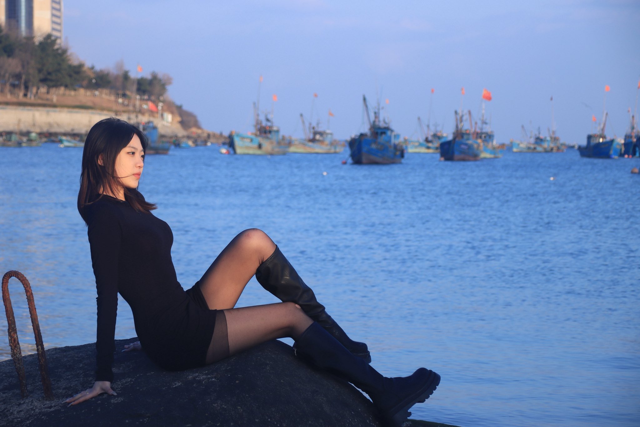 长头发和黑衬衫的女人站在海滩上。