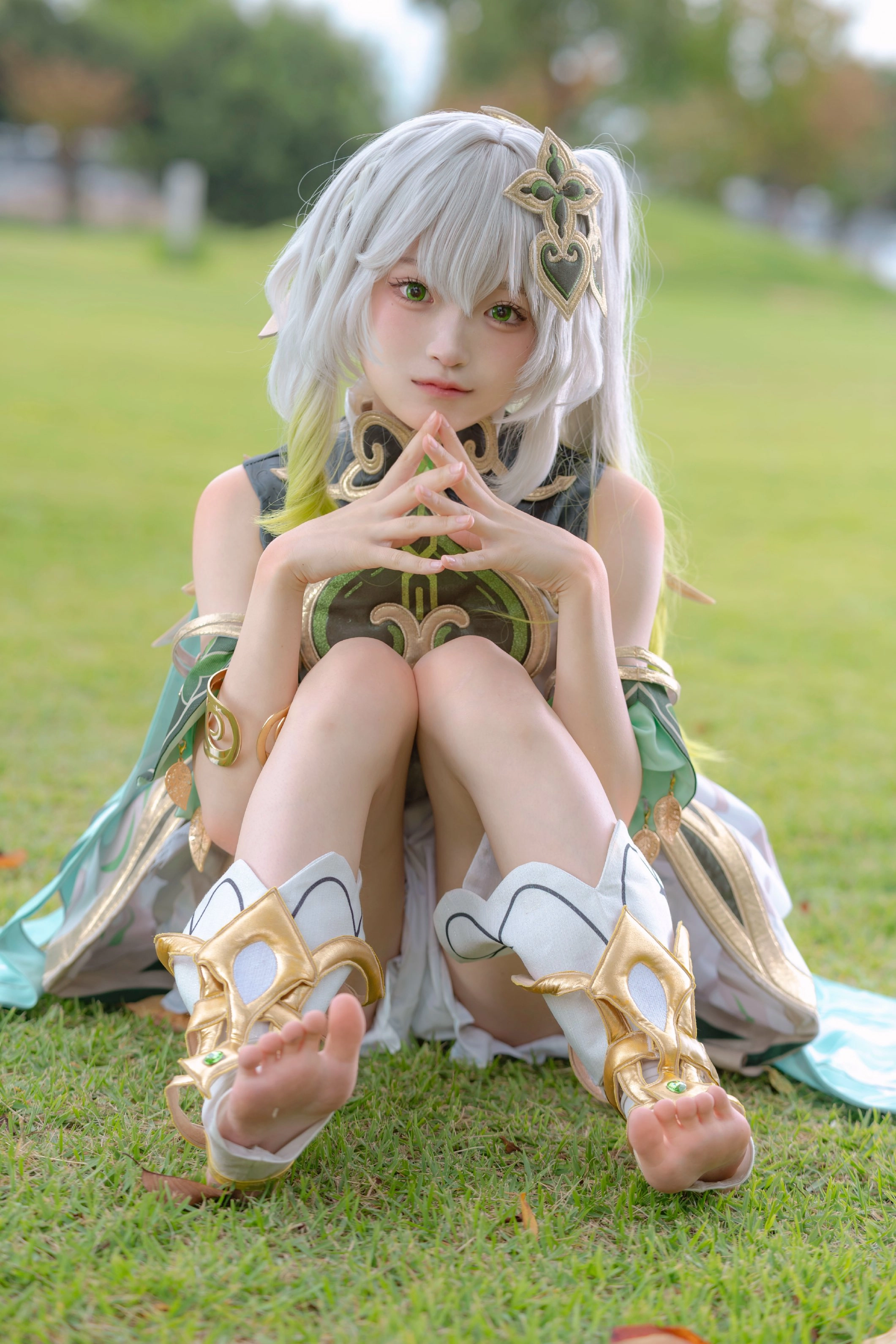 白头发和一件绿色的衣服的女人坐在草地上。