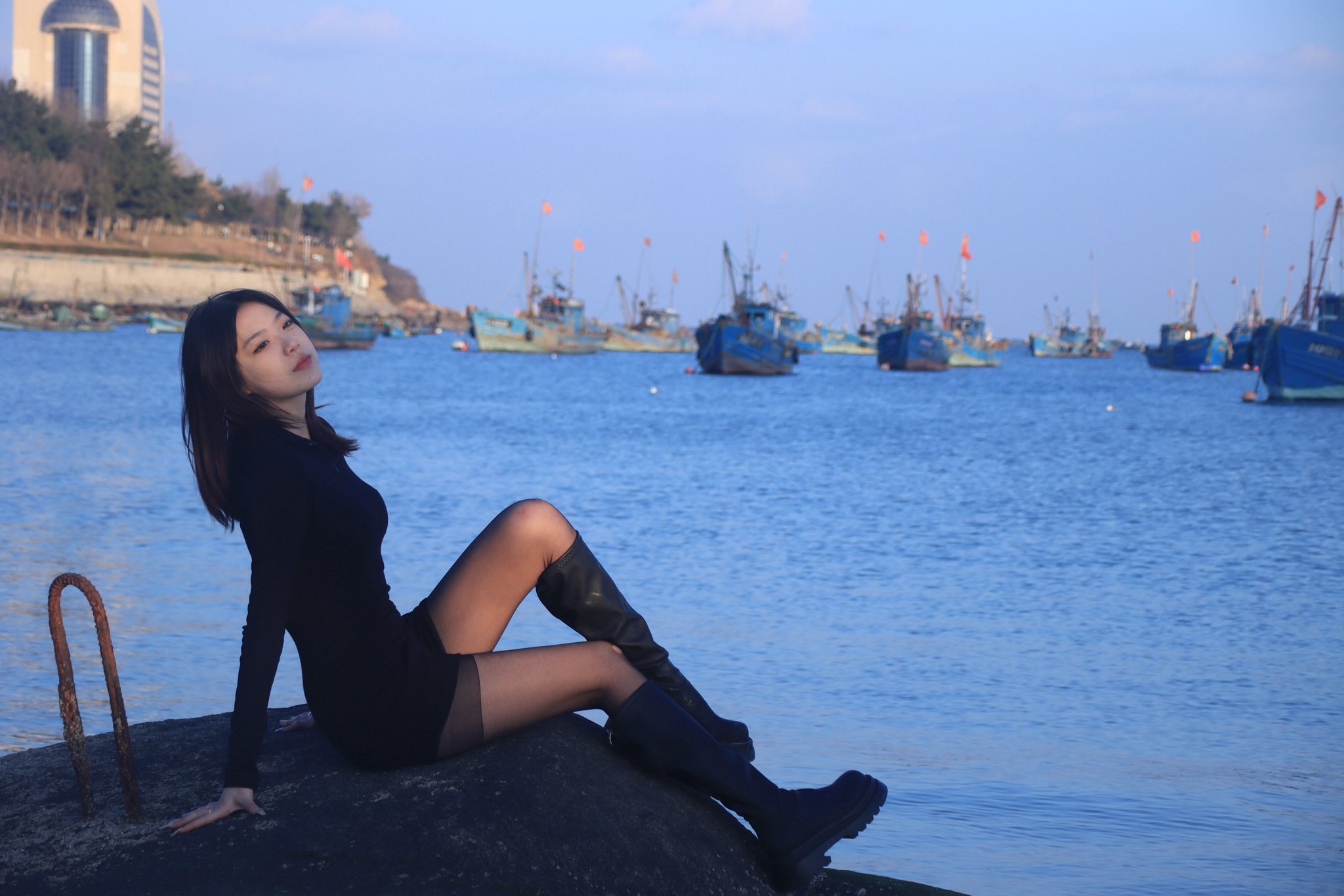 长头发和黑衬衫的女人站在海滩上。