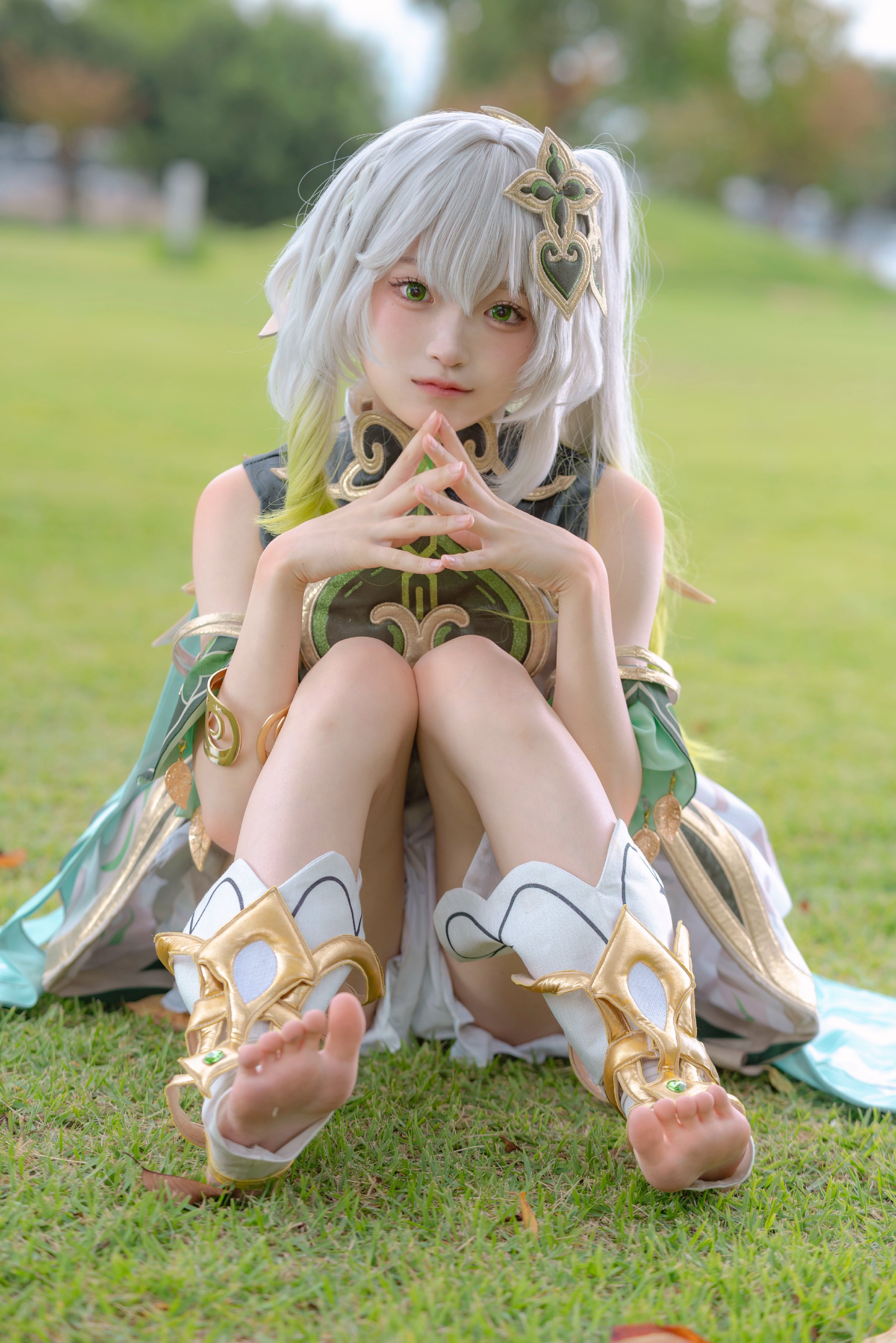 白头发和一件绿色的衣服的女人坐在草地上。