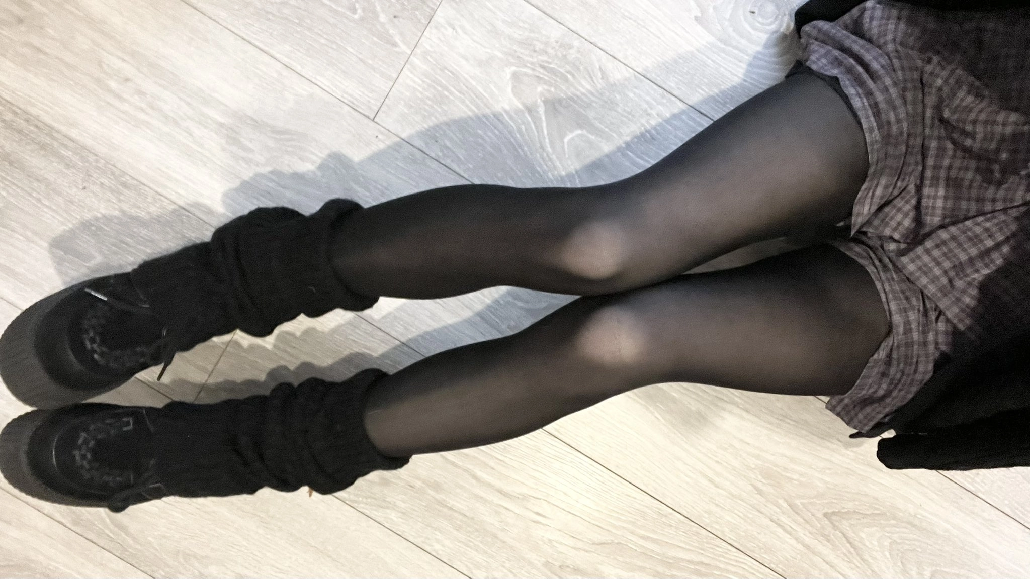 穿着黑色袜子和黑靴子的女人坐在地板上。