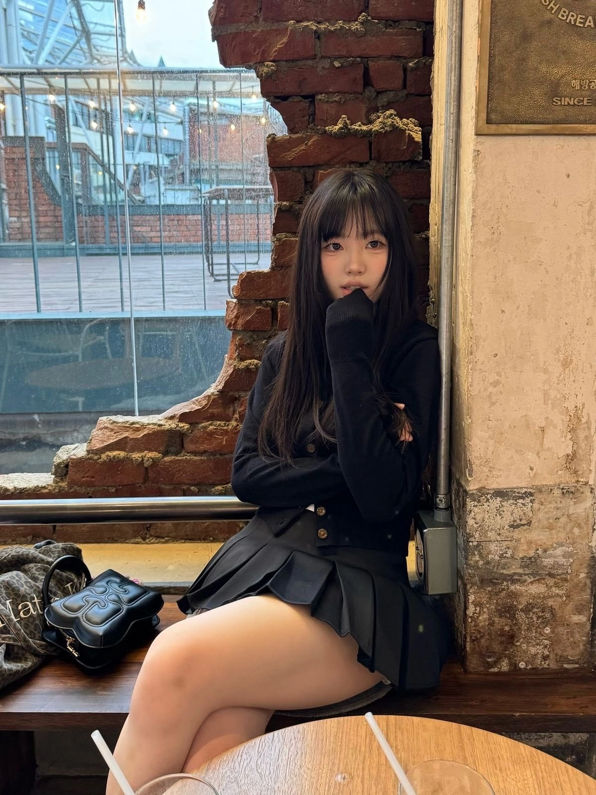 穿着黑色裙子和黑色夹克的女人坐在一个凳子上。