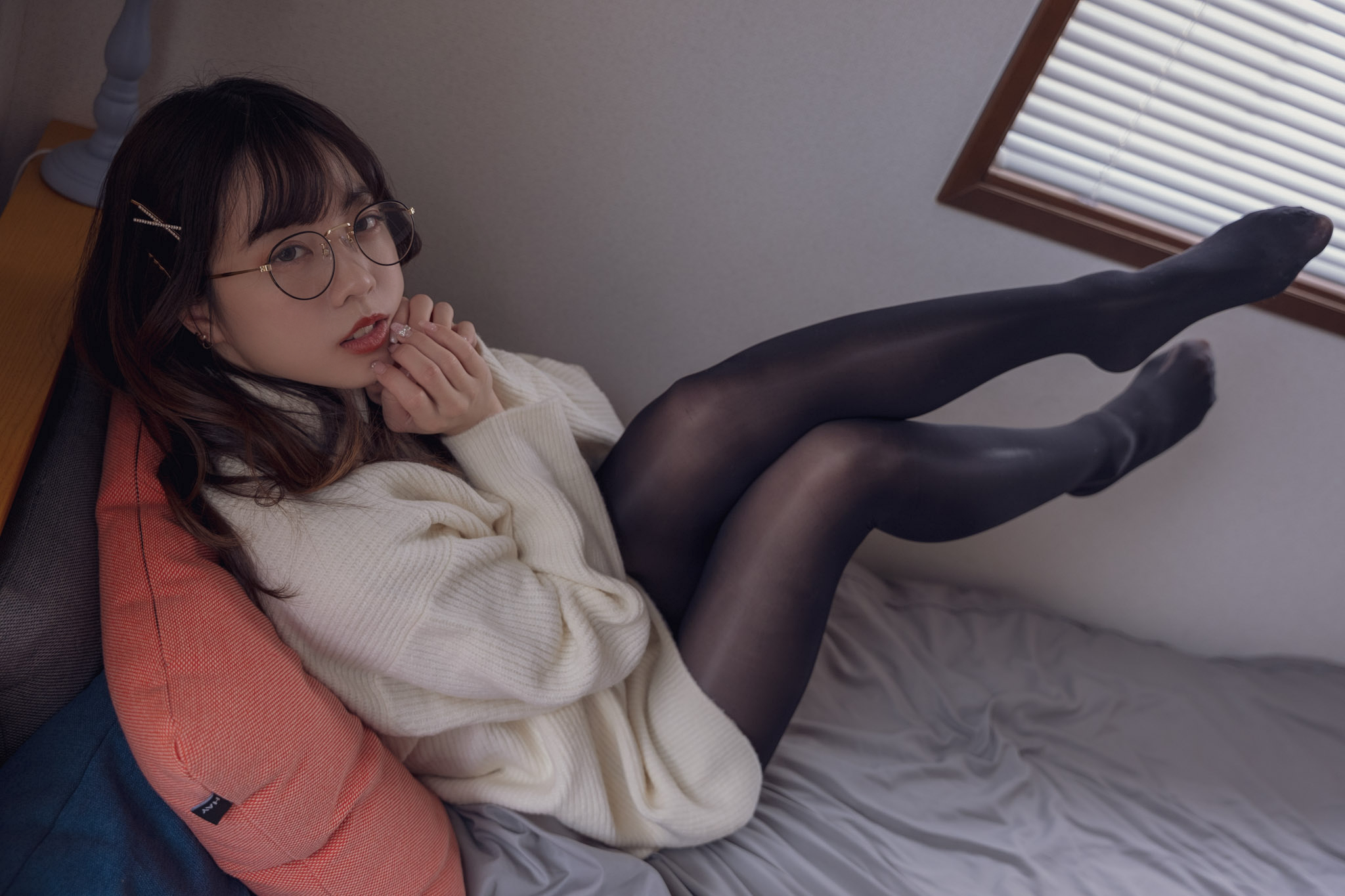 戴着眼镜和白色衬衫的女人坐在床上。