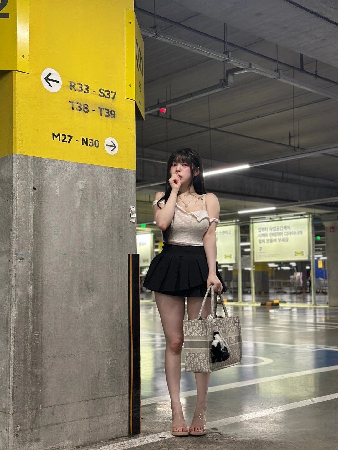 穿着白色衬衫和黑色裙子的女人站在一个标志旁边。