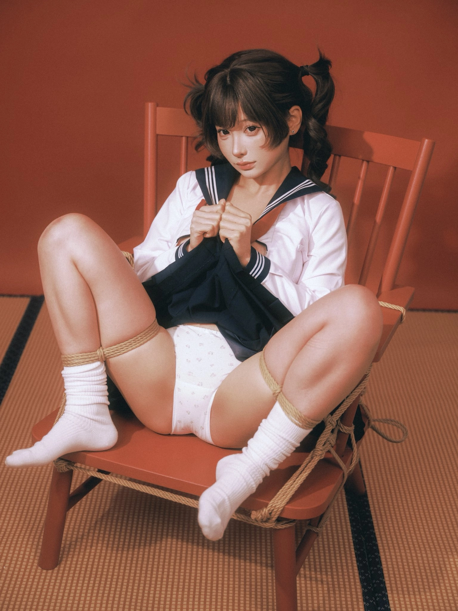 一位穿着蓝色衬衫和白色裤子的女人坐在红色椅子上。